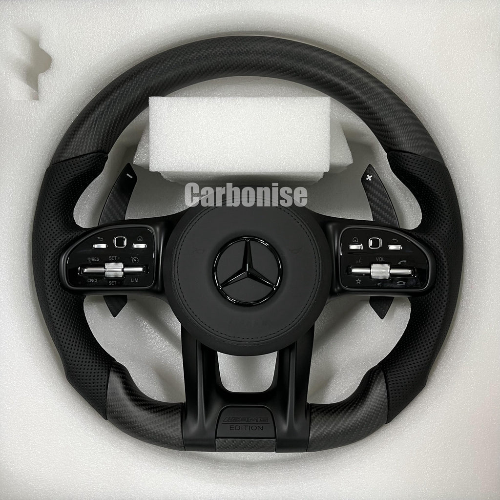 Custom Mercedes-Benz AMG steering wheel featuring a matte carbon fiber finish, black perforated leather side grips, and stealth black performance controls.