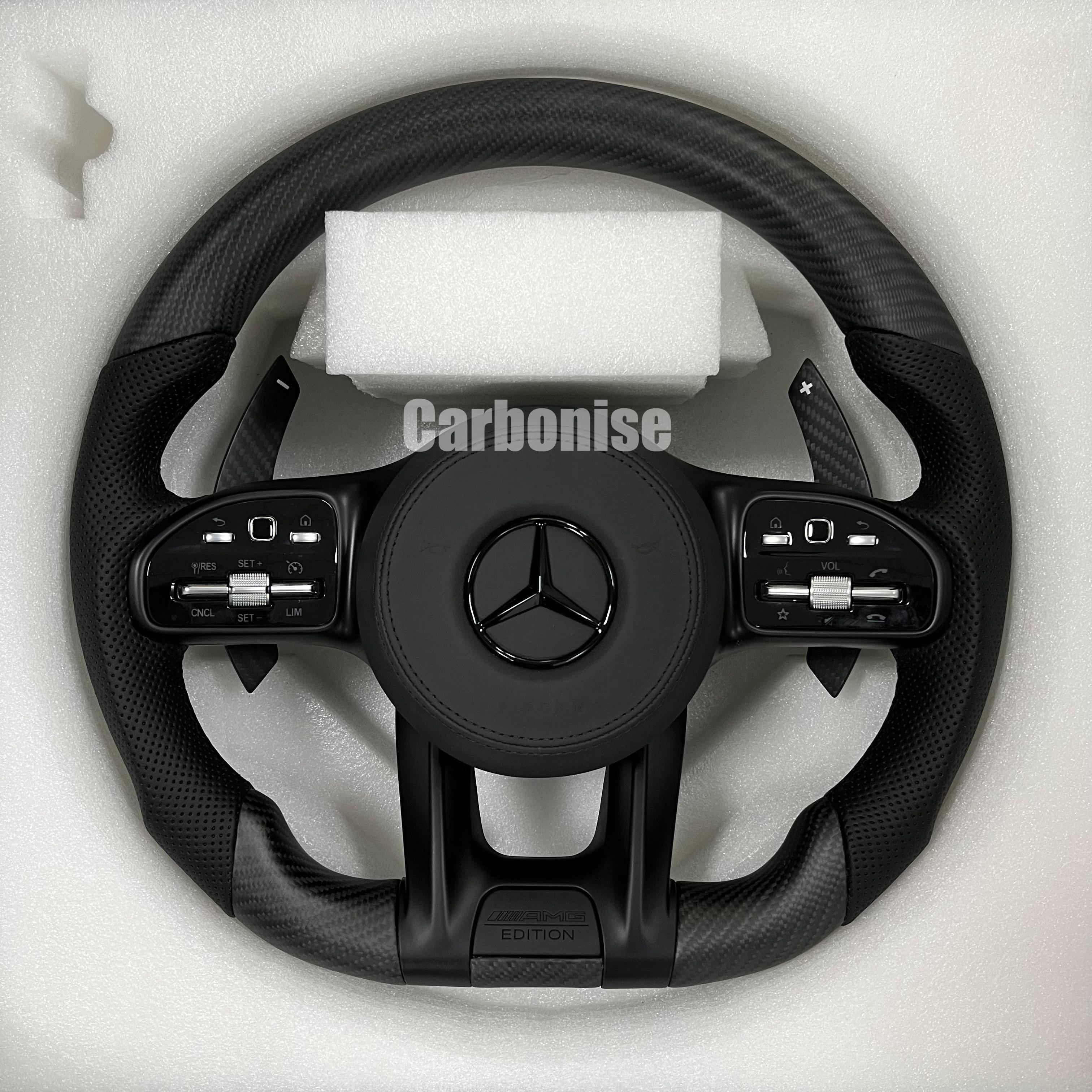 Custom Mercedes-Benz AMG steering wheel featuring a matte carbon fiber finish, black perforated leather side grips, and stealth black performance controls.