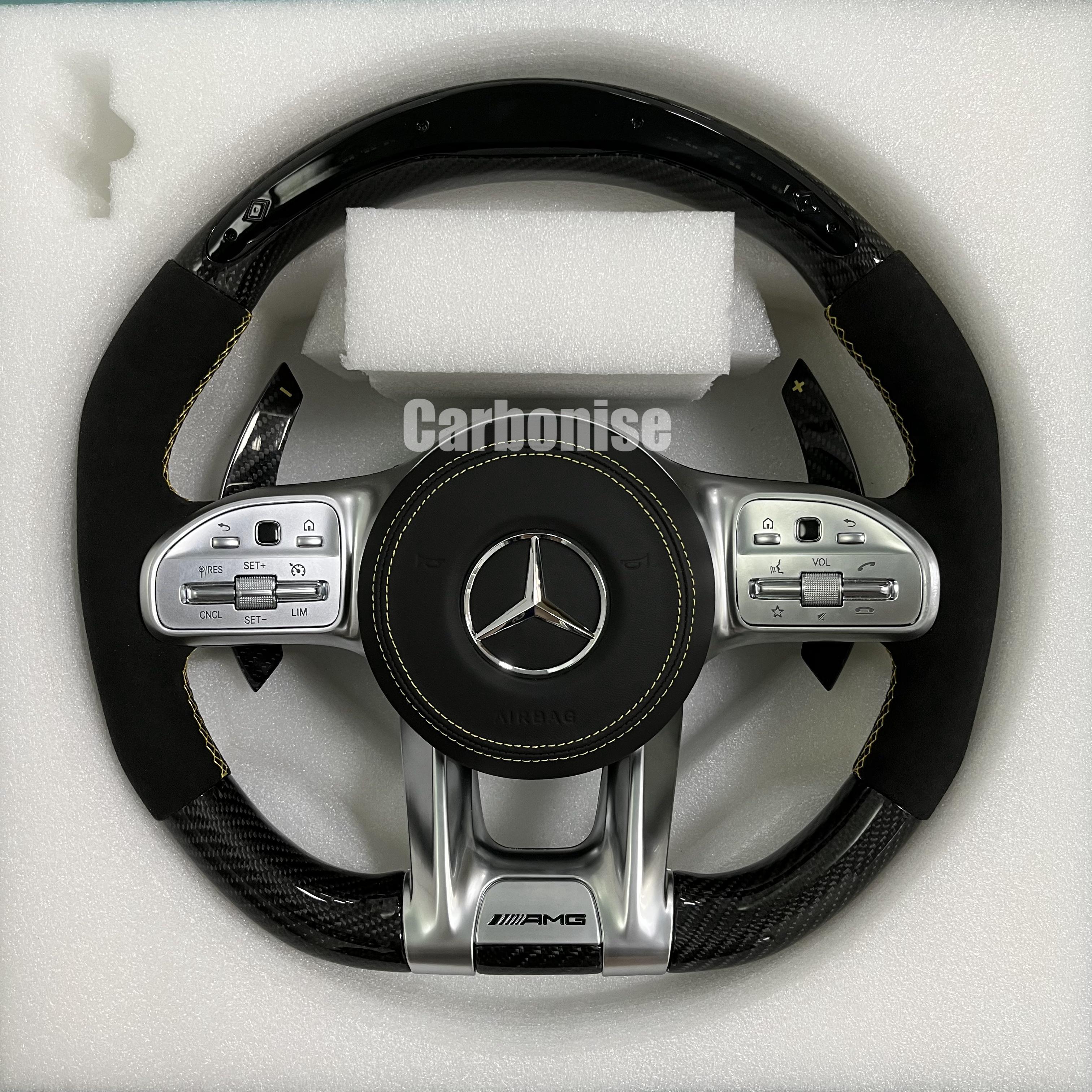 Custom Mercedes-Benz AMG steering wheel featuring a gloss carbon fiber top and bottom, black Alcantara side grips with yellow stitching, and silver controls.