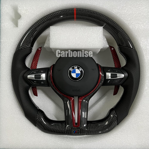 Custom BMW M steering wheel featuring gloss carbon fiber, a red top racing stripe, red tinted carbon accents, and perforated leather side grips.