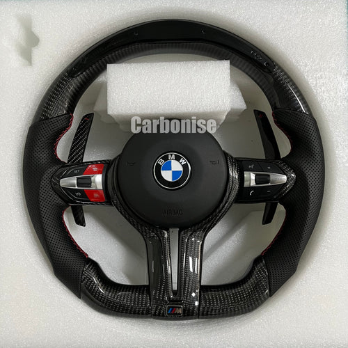 Custom BMW M performance steering wheel featuring gloss carbon fiber, black perforated leather side grips with red stitching, and red button accents.
