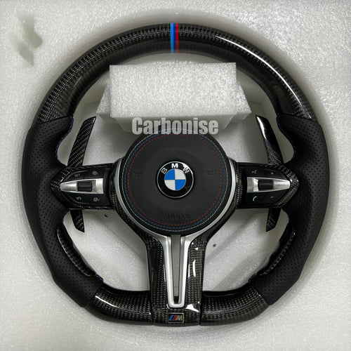 Custom BMW M performance steering wheel featuring high-gloss carbon fiber, a signature M-tri color top racing stripe, and black perforated leather grips.