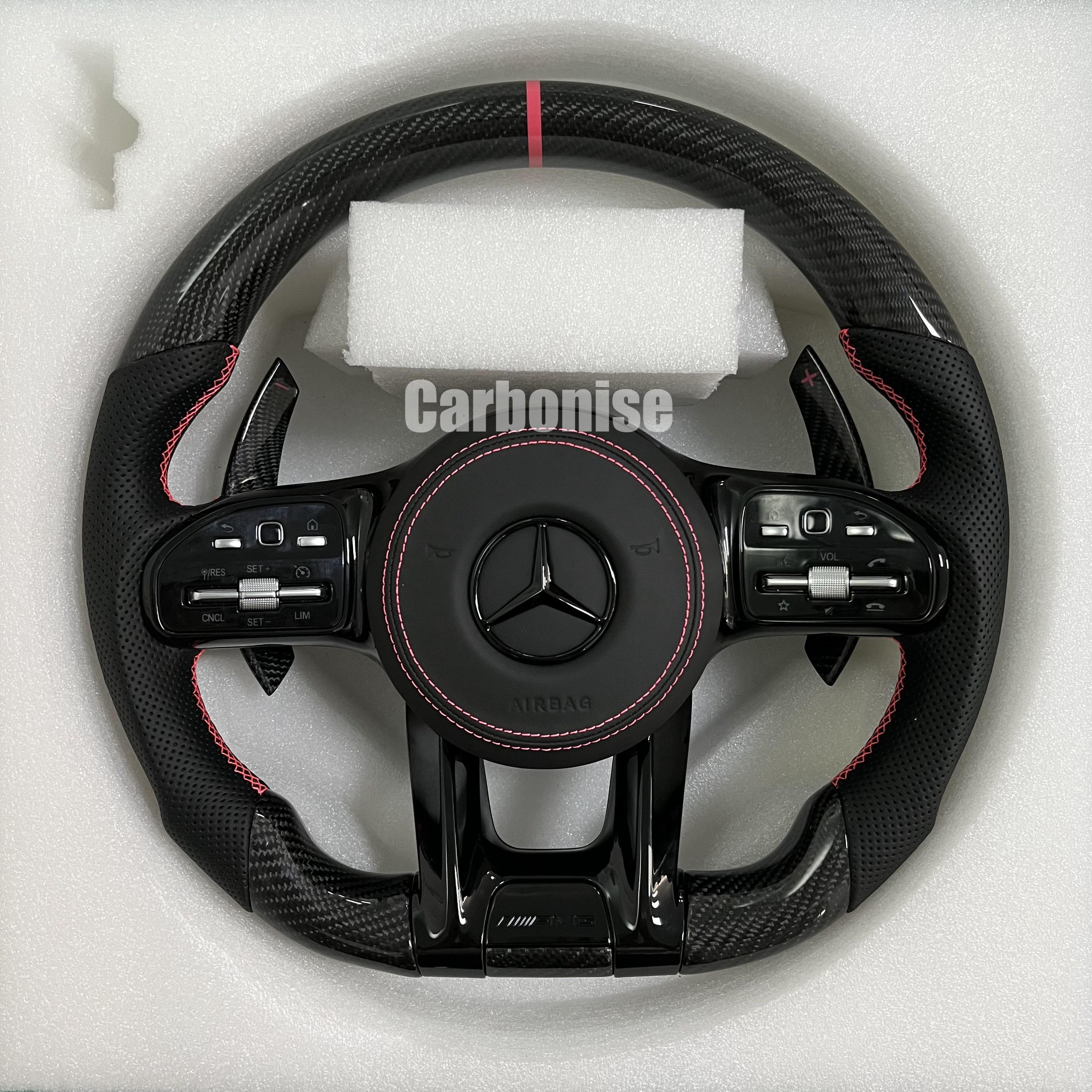 Custom Mercedes-Benz AMG steering wheel featuring high-gloss carbon fiber, a red top racing stripe, and black perforated leather side grips with red stitching.