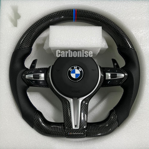 BMW M Performance steering wheel featuring gloss carbon fiber, a signature blue, light blue, and red M-tri color top racing stripe, and black perforated leather side grips with blue stitching.