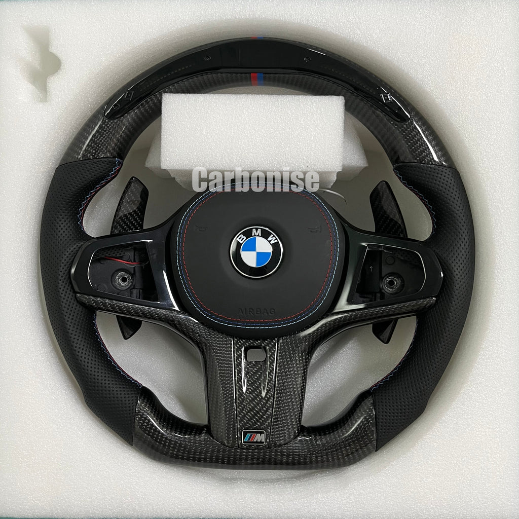 Custom BMW M steering wheel featuring high-gloss carbon fiber, a signature M-tri color top racing stripe, and black perforated leather side grips.