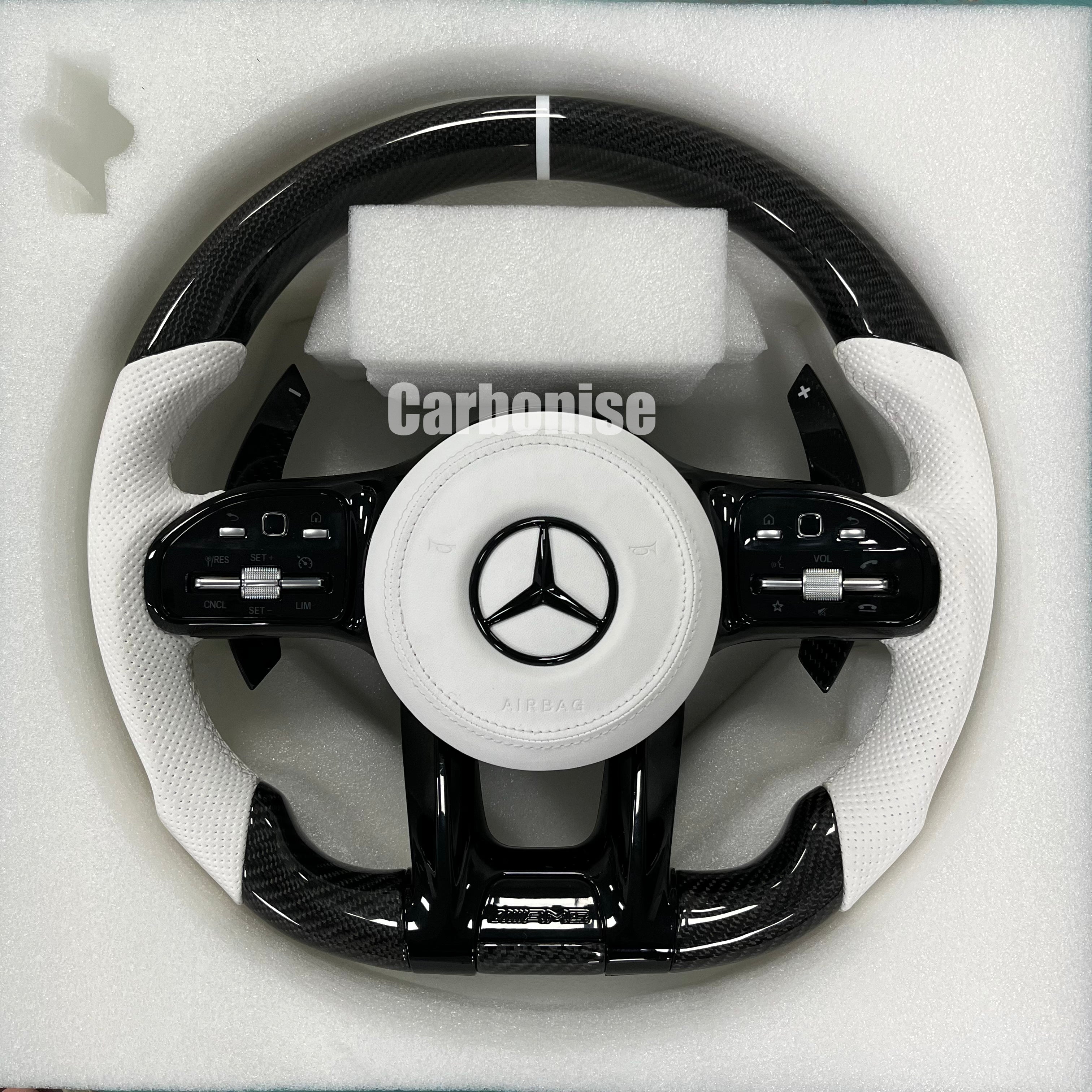 Custom Mercedes-Benz AMG steering wheel featuring gloss carbon fiber, white perforated leather grips, and a clean silver top racing stripe.