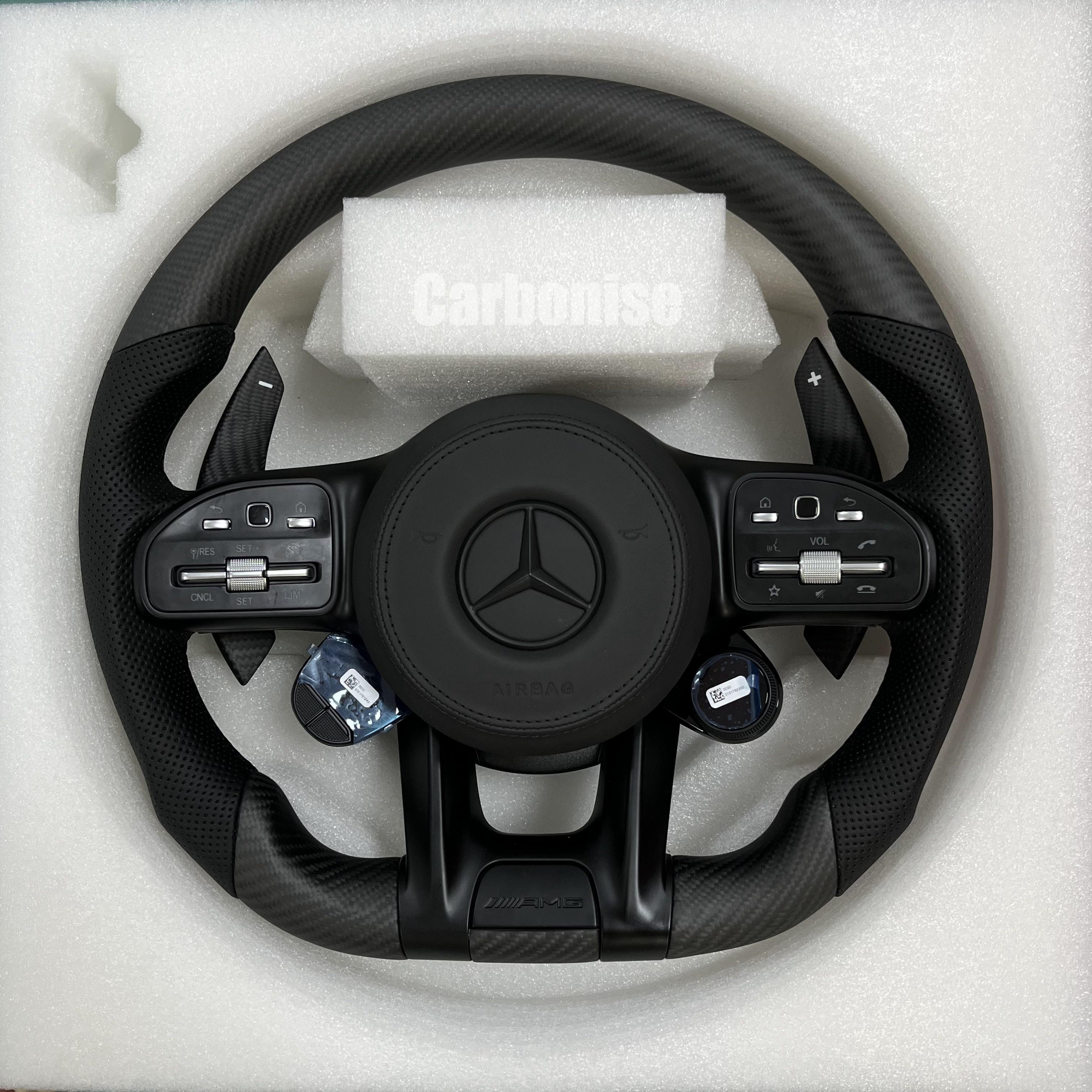 Custom Mercedes-Benz AMG steering wheel featuring matte carbon fiber, integrated digital drive mode dials, and black perforated leather side grips.