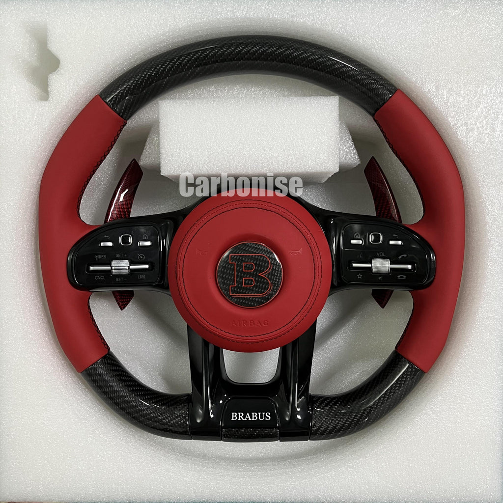 Custom Mercedes-Benz steering wheel featuring high-gloss carbon fiber, a red leather Brabus-branded airbag cover, and matching red leather side grips.