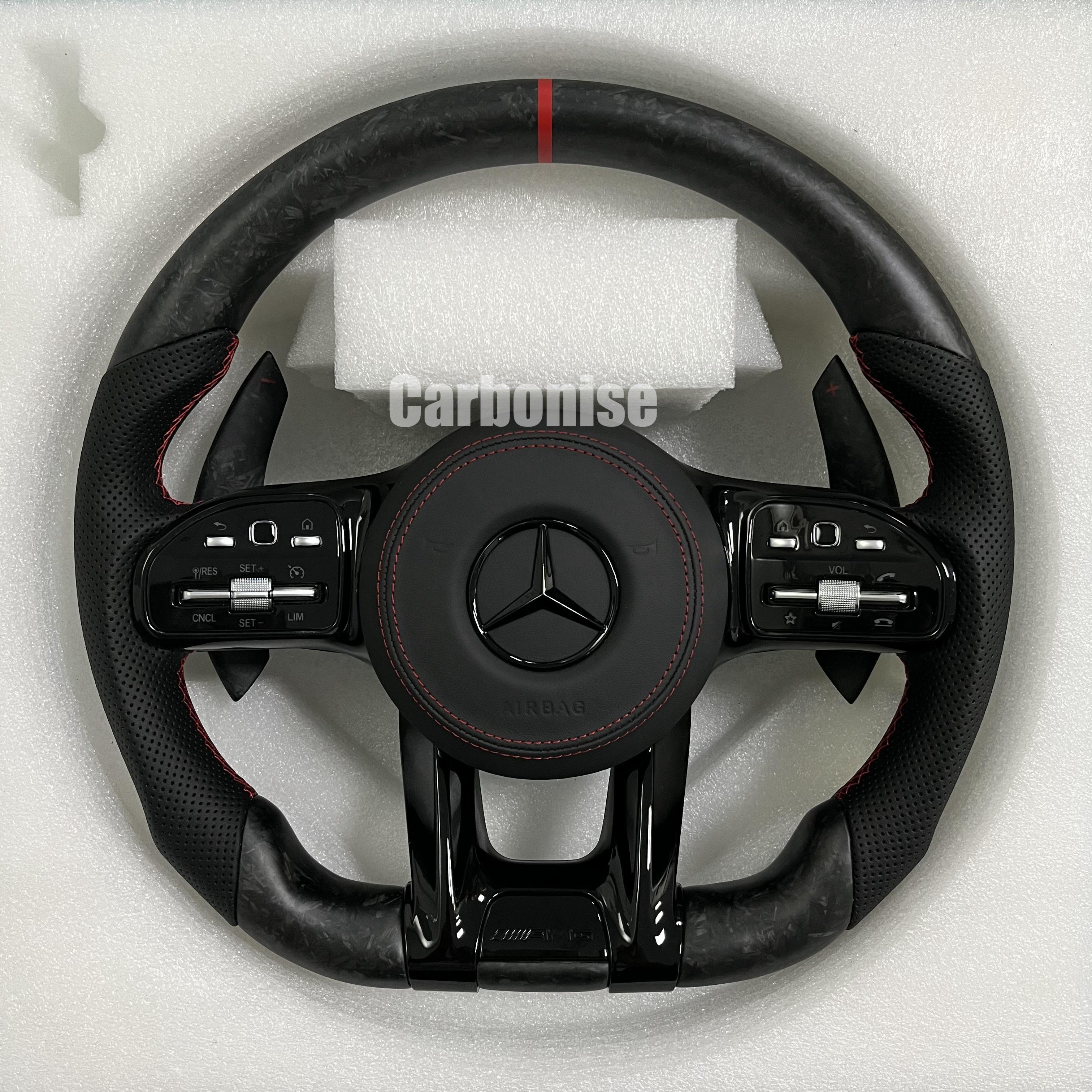 Custom Mercedes-Benz AMG steering wheel featuring matte forged carbon fiber, a red top racing stripe, and black perforated leather grips with red stitching.