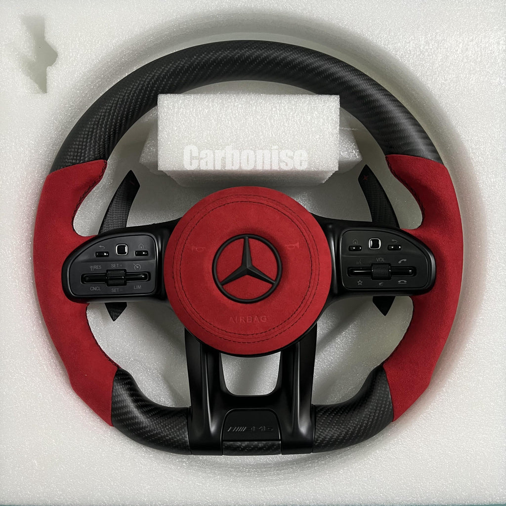 Custom Mercedes-Benz AMG steering wheel featuring a matte carbon fiber finish, a vibrant red Alcantara airbag cover, and matching red Alcantara side grips.
