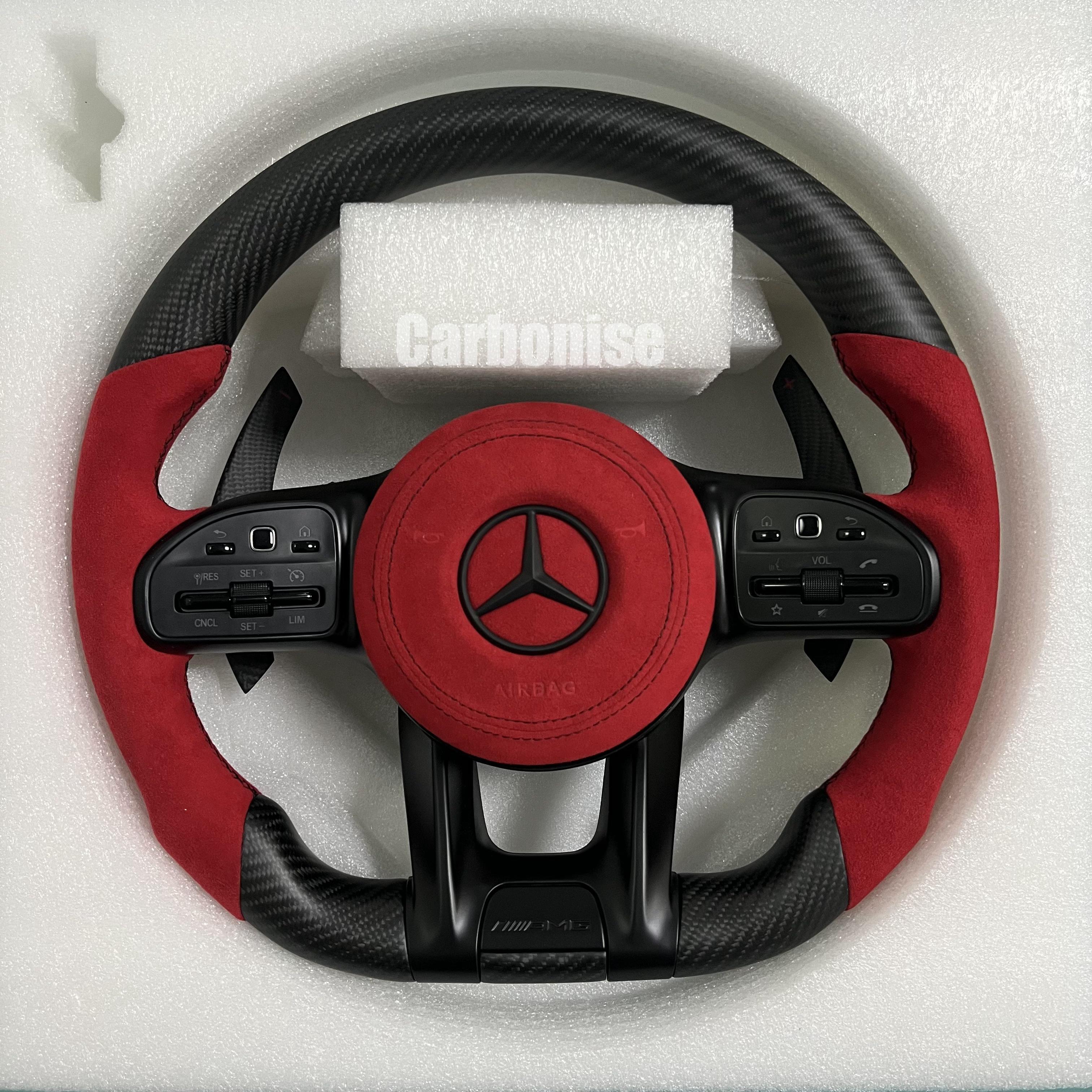 Custom Mercedes-Benz AMG steering wheel featuring a matte carbon fiber finish, a vibrant red Alcantara airbag cover, and matching red Alcantara side grips.