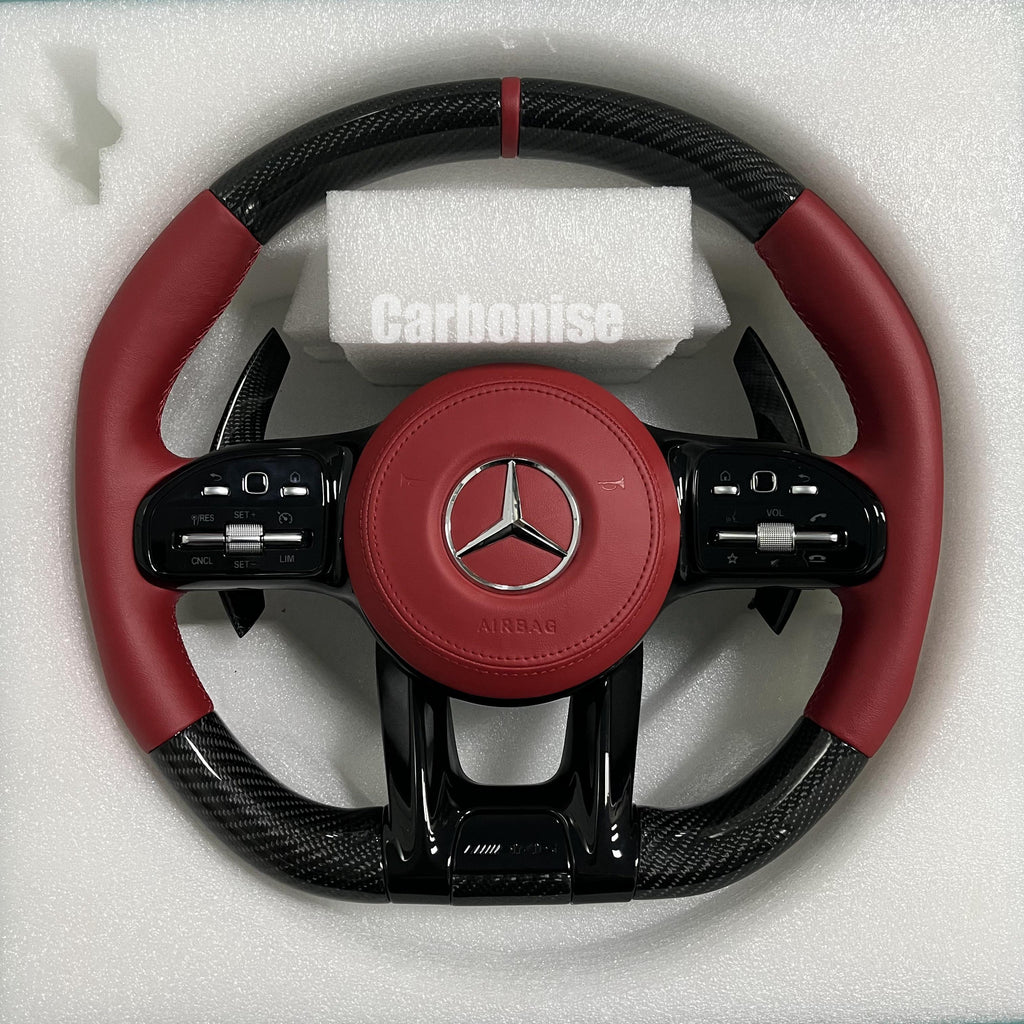 Custom Mercedes-Benz AMG steering wheel featuring high-gloss carbon fiber, a vibrant red leather airbag cover, and matching red perforated leather side grips.