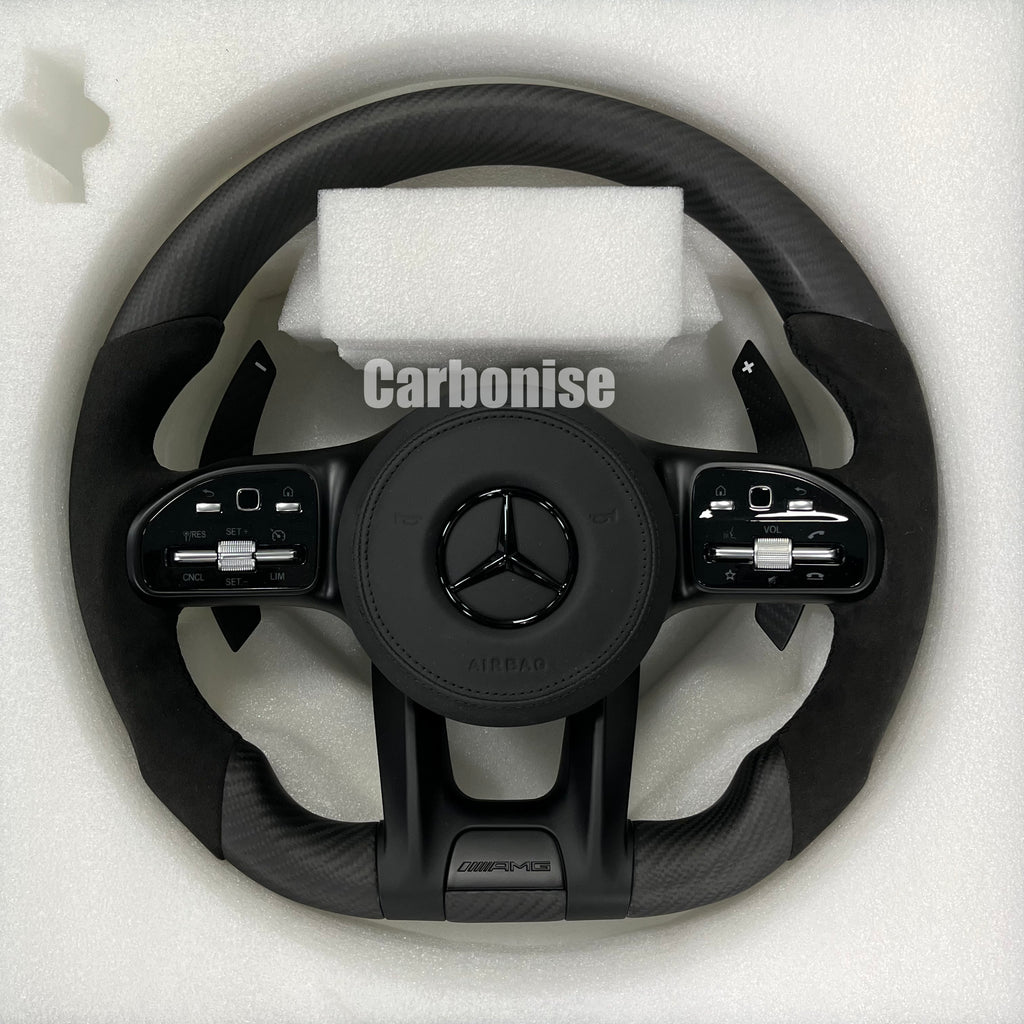 Custom Mercedes-Benz AMG performance steering wheel featuring a matte carbon fiber finish, black Alcantara side grips, and integrated stealth black controls.