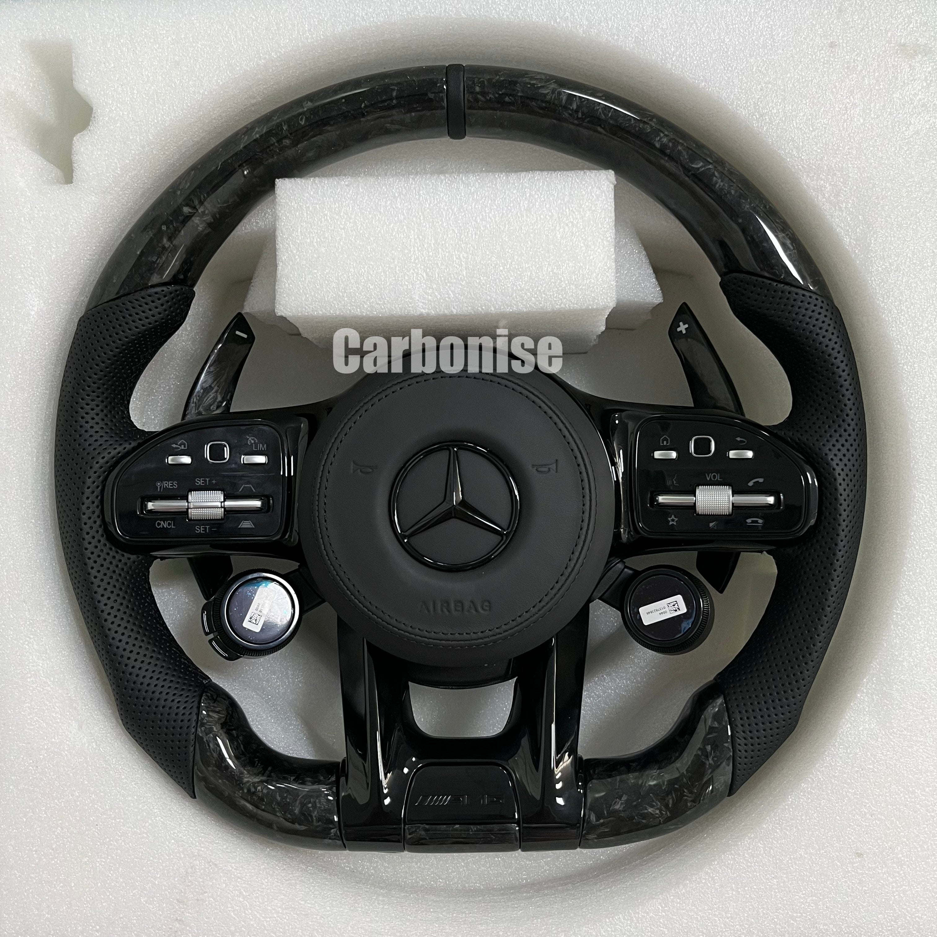 Custom Mercedes-Benz AMG steering wheel featuring marbled forged carbon fiber, integrated digital drive mode dials, and black perforated leather side grips.