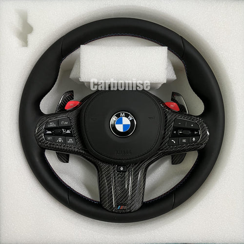 Custom BMW M performance steering wheel featuring a full black smooth leather wrap, red M1/M2 button accents, and high-gloss carbon fiber trim.