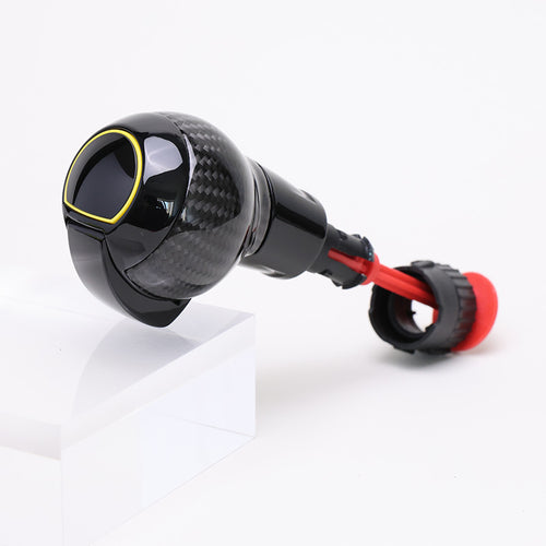Carbon fibre gear shift knob with gloss black finish, red accent ring, and rounded performance design.