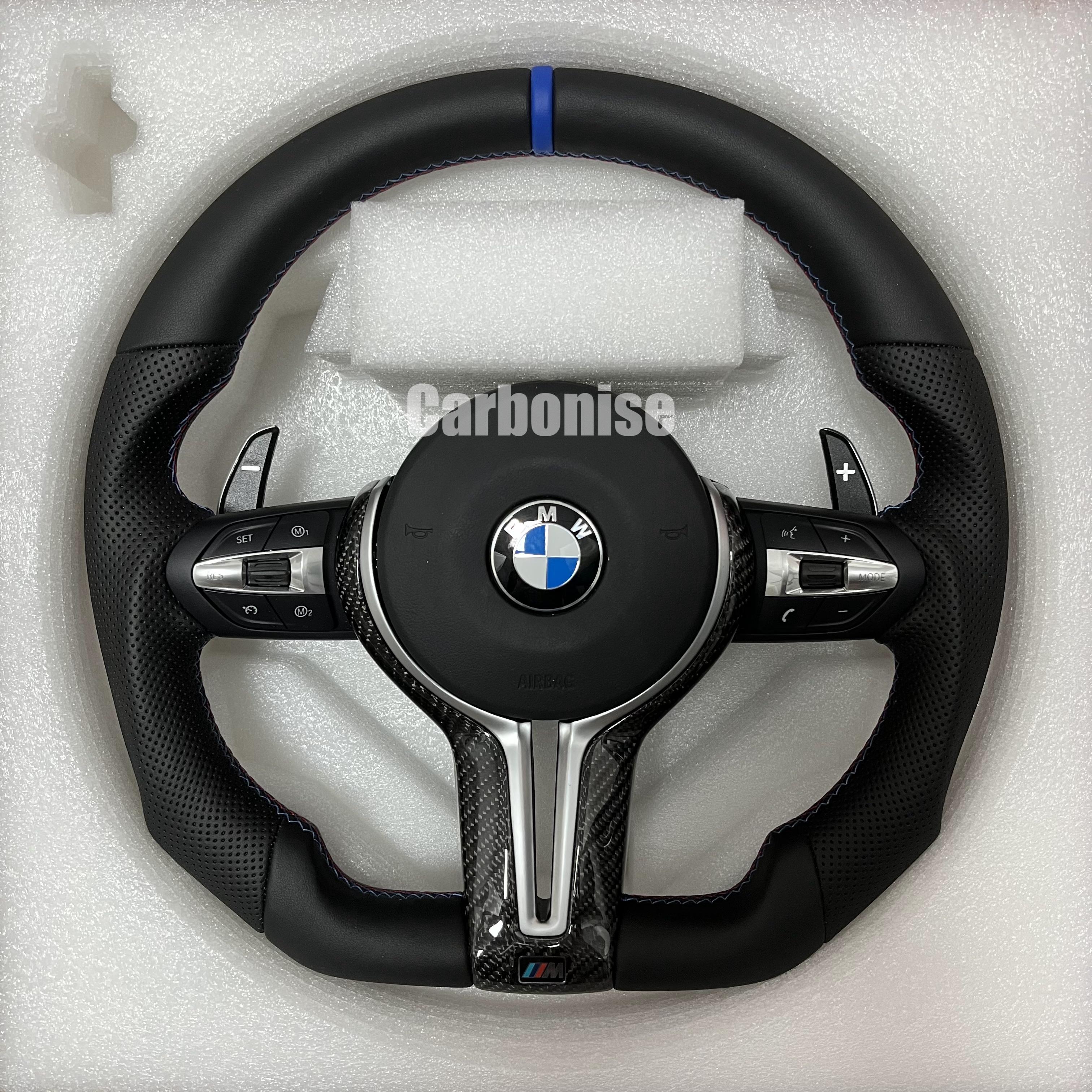 Custom BMW M Performance steering wheel featuring a blue top racing stripe, a mix of black smooth and perforated leather grips with blue stitching, and high-gloss carbon fiber trim.