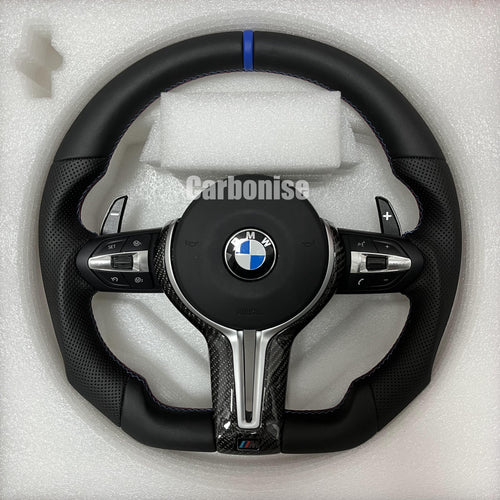 Custom BMW M Performance steering wheel featuring a blue top racing stripe, a mix of black smooth and perforated leather grips with blue stitching, and high-gloss carbon fiber trim.