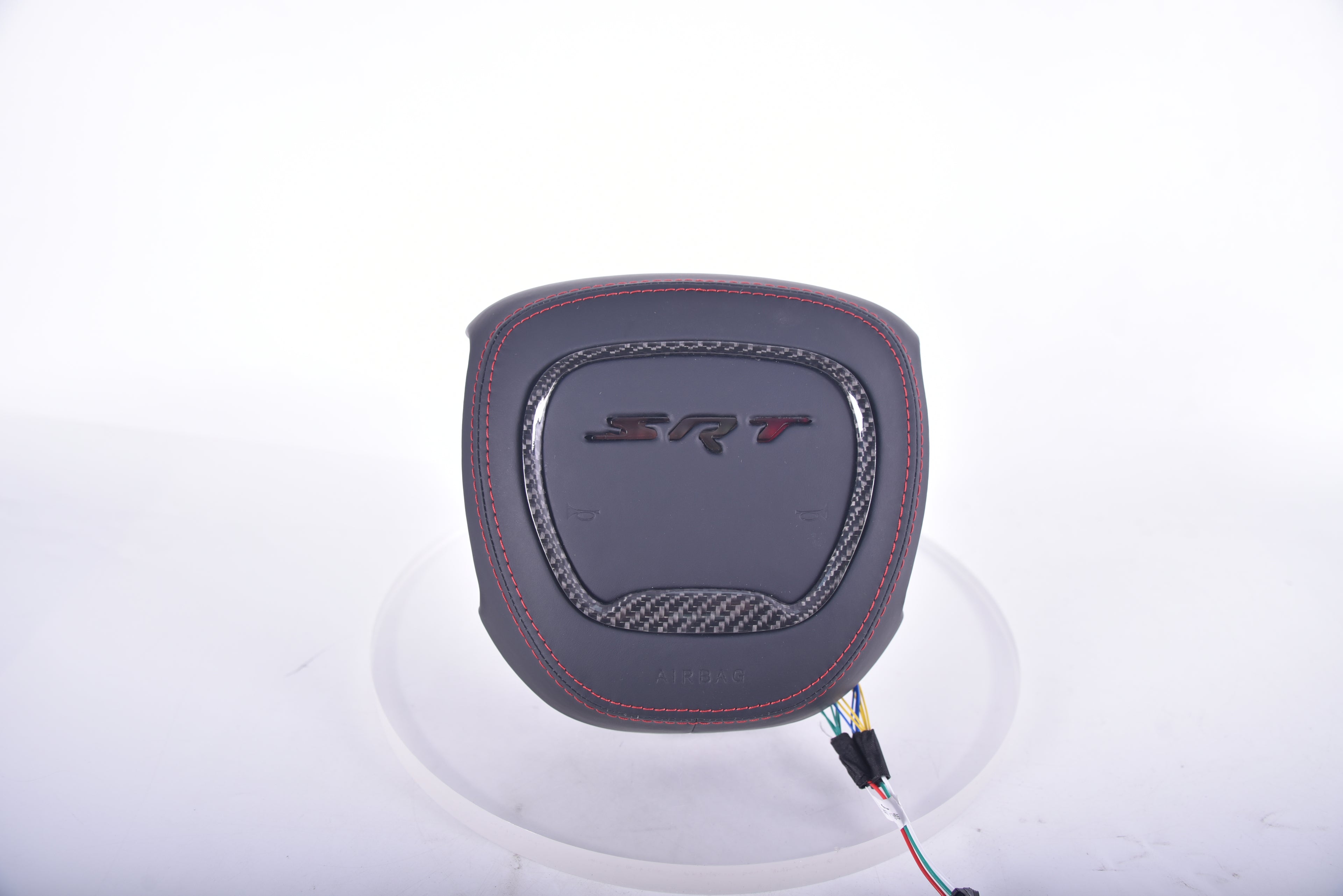 SRT carbon fibre airbag cover with black leather finish, red stitching, carbon fibre trim insert, and embossed SRT logo.