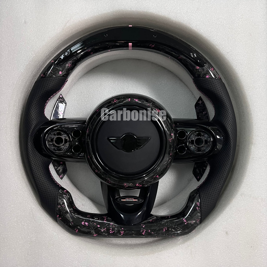 Custom Mini Cooper forged carbon steering wheel with pink carbon flakes, perforated black leather grips, paddle shifter cutouts, and flat-bottom performance design.