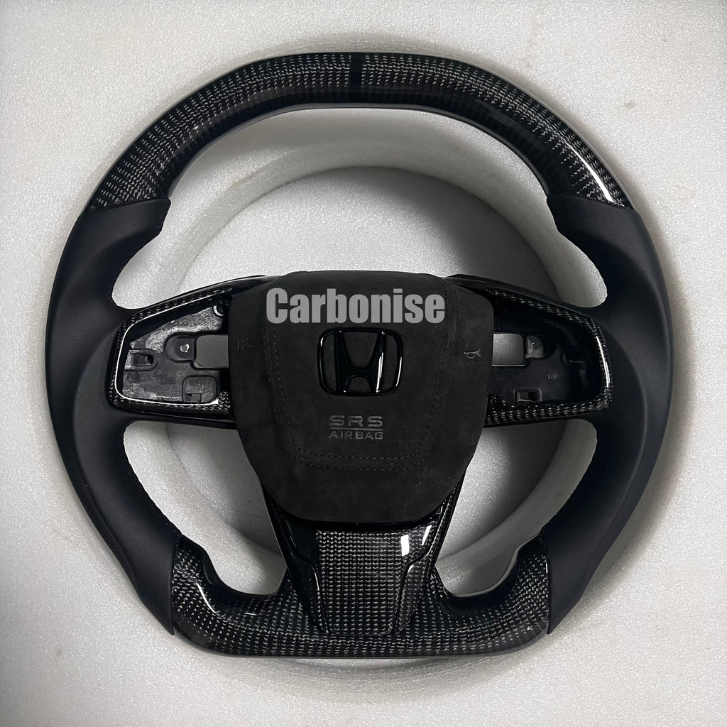 Custom Honda carbon fiber steering wheel with gloss carbon top and bottom, smooth black leather side grips, Alcantara airbag cover, and flat bottom shape.
