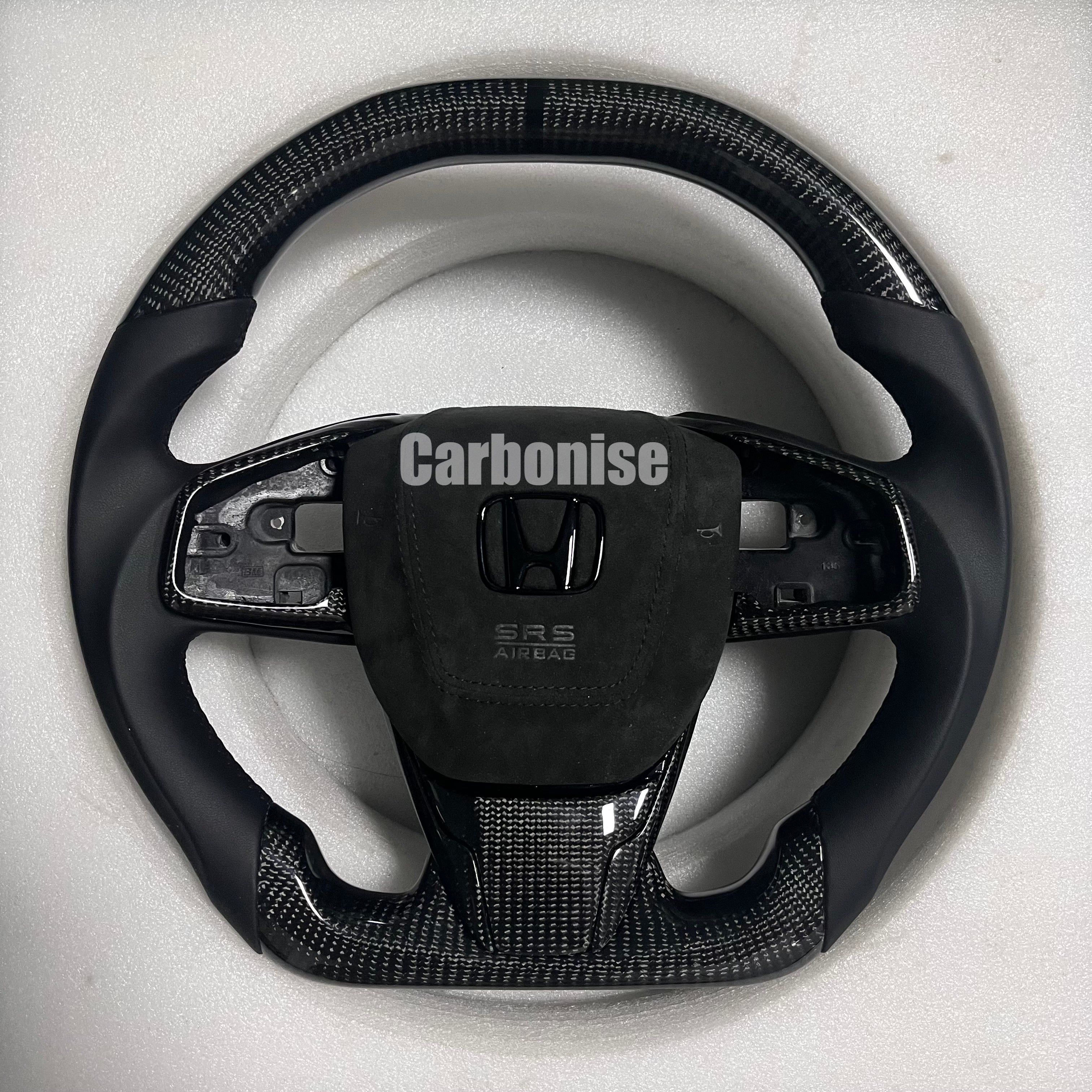 Custom Honda carbon fiber steering wheel with gloss carbon top and bottom, smooth black leather side grips, Alcantara airbag cover, and flat bottom shape.