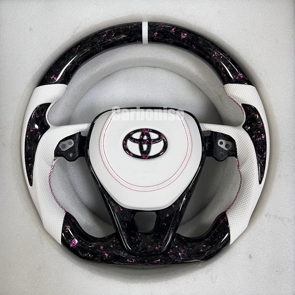 Carbonise Toyota carbon fiber steering wheel with pink forged carbon, white perforated leather grips, and custom pink stitching
