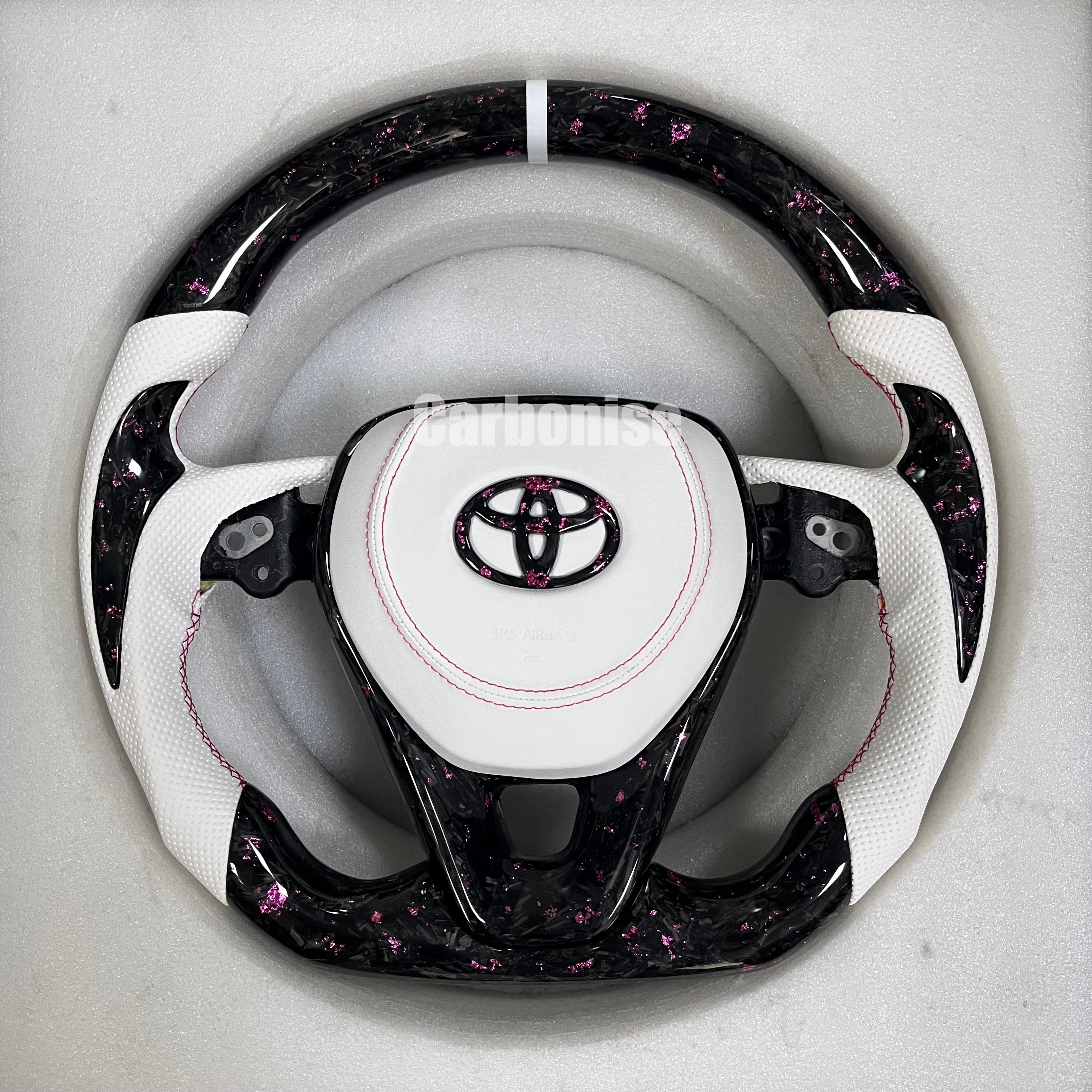 Carbonise Toyota carbon fiber steering wheel with pink forged carbon, white perforated leather grips, and custom pink stitching