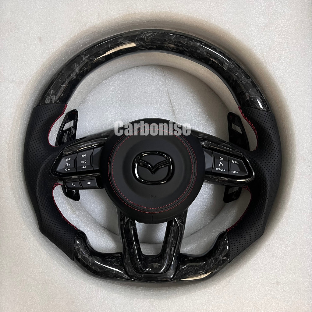 Carbonise Mazda forged carbon steering wheel with black perforated leather grip and red stitching

Red stitching airbag cover leather