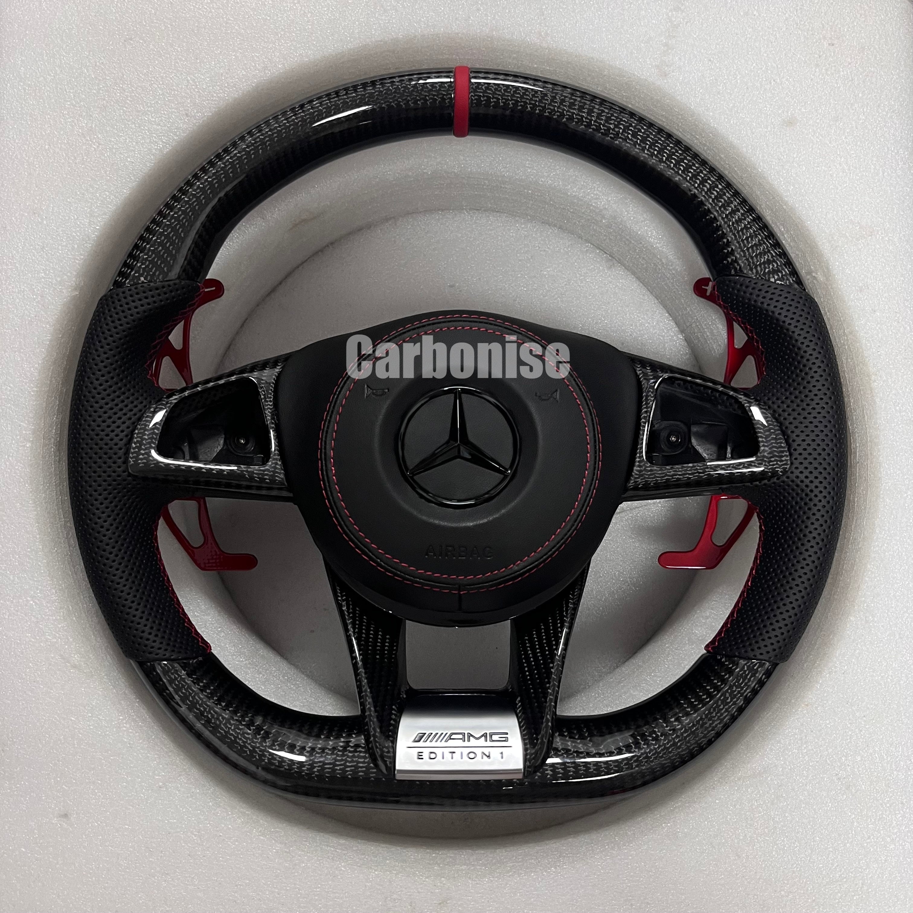 Custom Mercedes-Benz AMG steering wheel featuring gloss carbon fiber, a red top racing stripe, red paddle shifters, and black perforated leather side grips.
