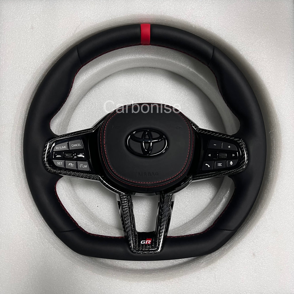 Carbonise leather Toyota GR steering wheel with red center stripe, carbon fiber trim, red stitching, flat bottom design, and OEM multifunction buttons