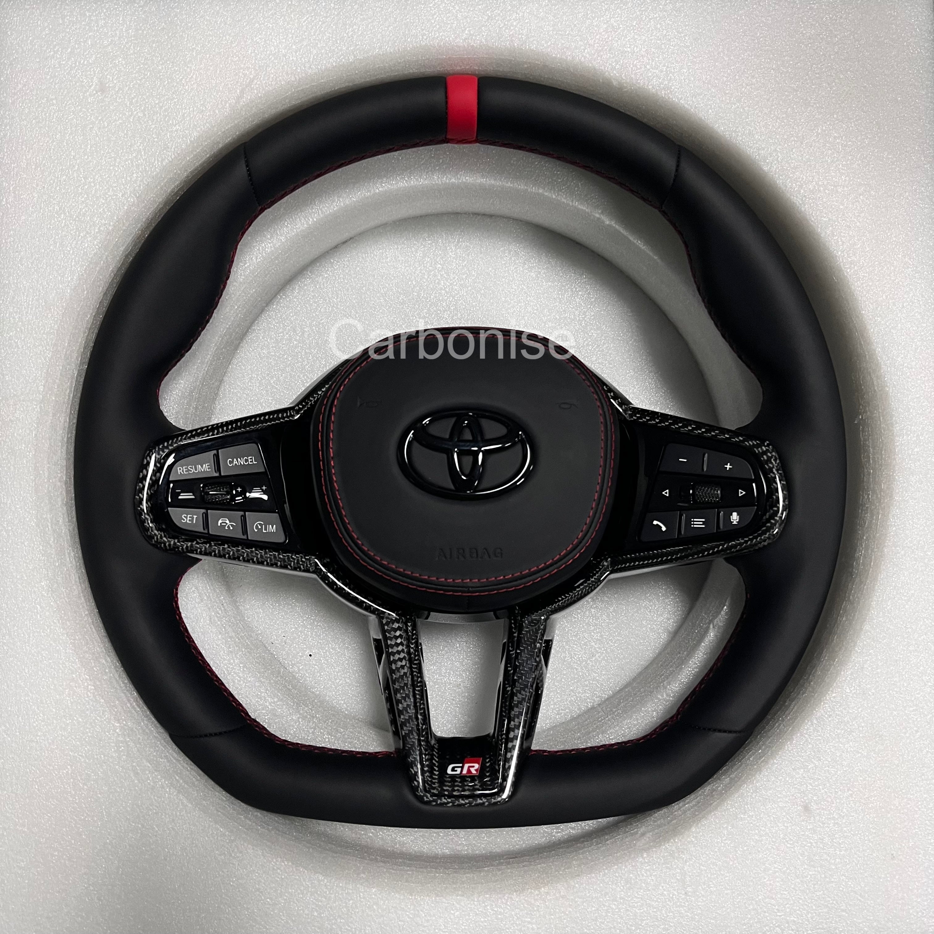 Carbonise leather Toyota GR steering wheel with red center stripe, carbon fiber trim, red stitching, flat bottom design, and OEM multifunction buttons