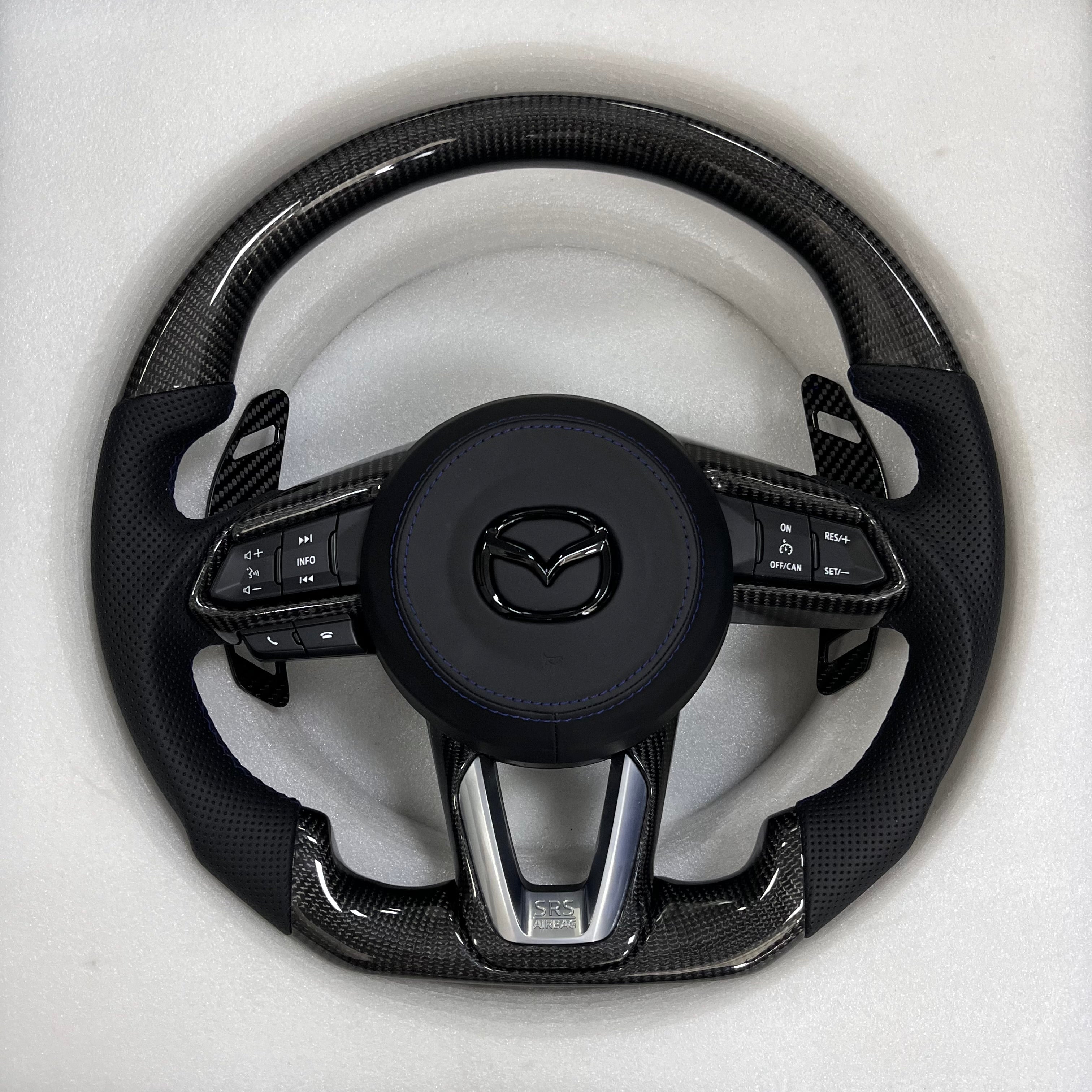 Carbonise Mazda carbon fiber steering wheel with black perforated leather grip and blue stitching