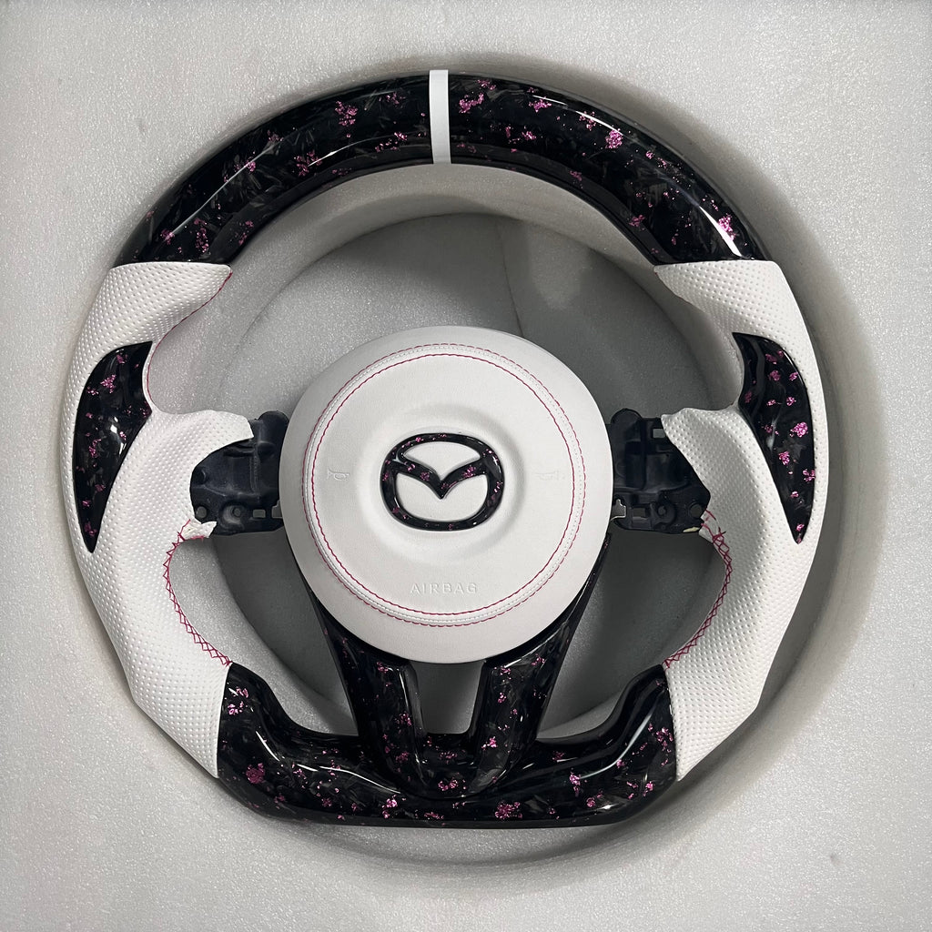 Carbonise Mazda pink forged carbon steering wheel with white perforated leather grip and pink stitching
airbag cover
