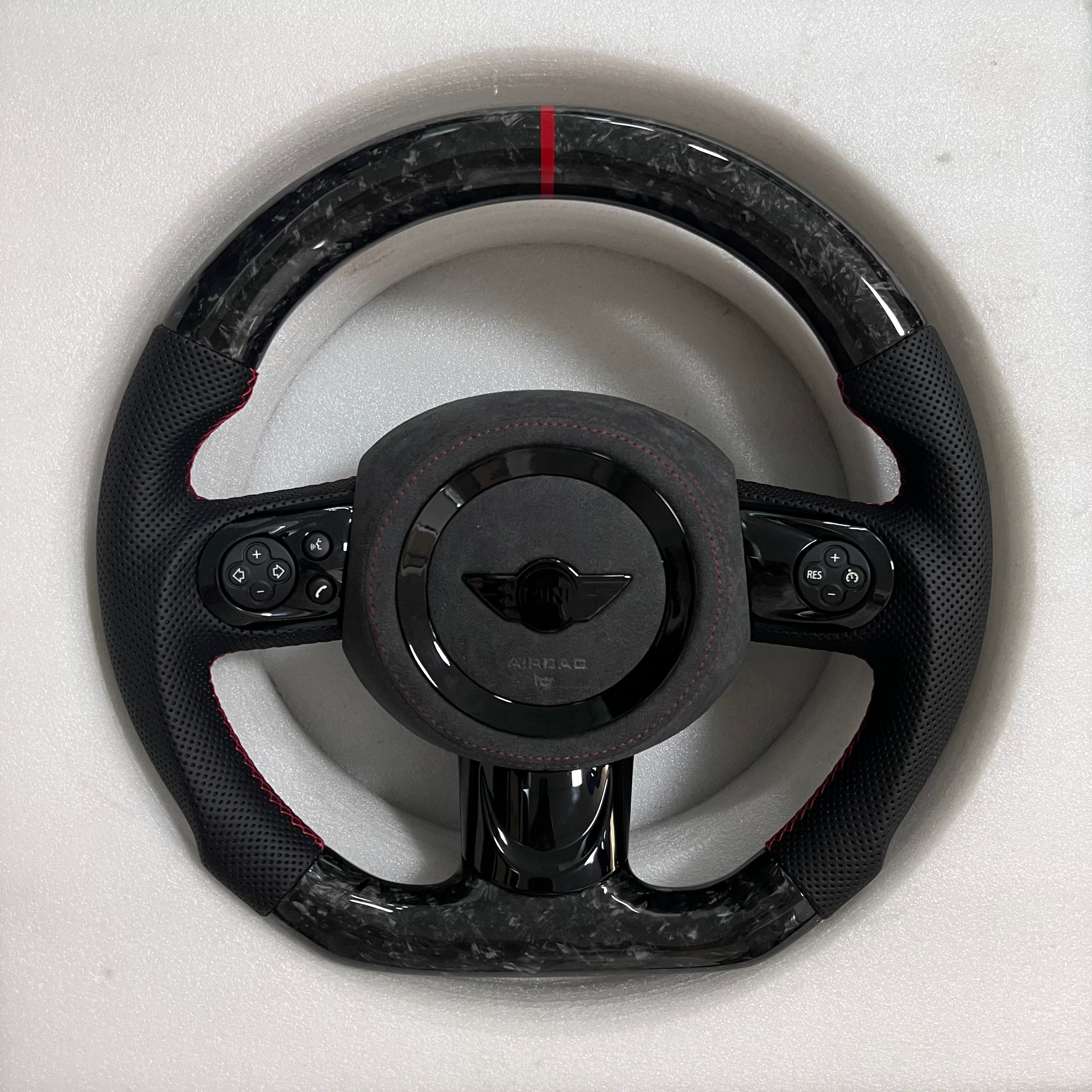 Custom Mini forged carbon steering wheel with perforated black leather grips, red center stripe, gloss black spokes, and flat-bottom performance design.