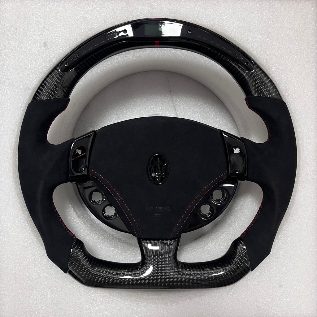 Custom Maserati carbon fibre steering wheel with black Alcantara side grips, red contrast stitching, gloss carbon trim, and a flat-bottom performance shape. Led Shift light