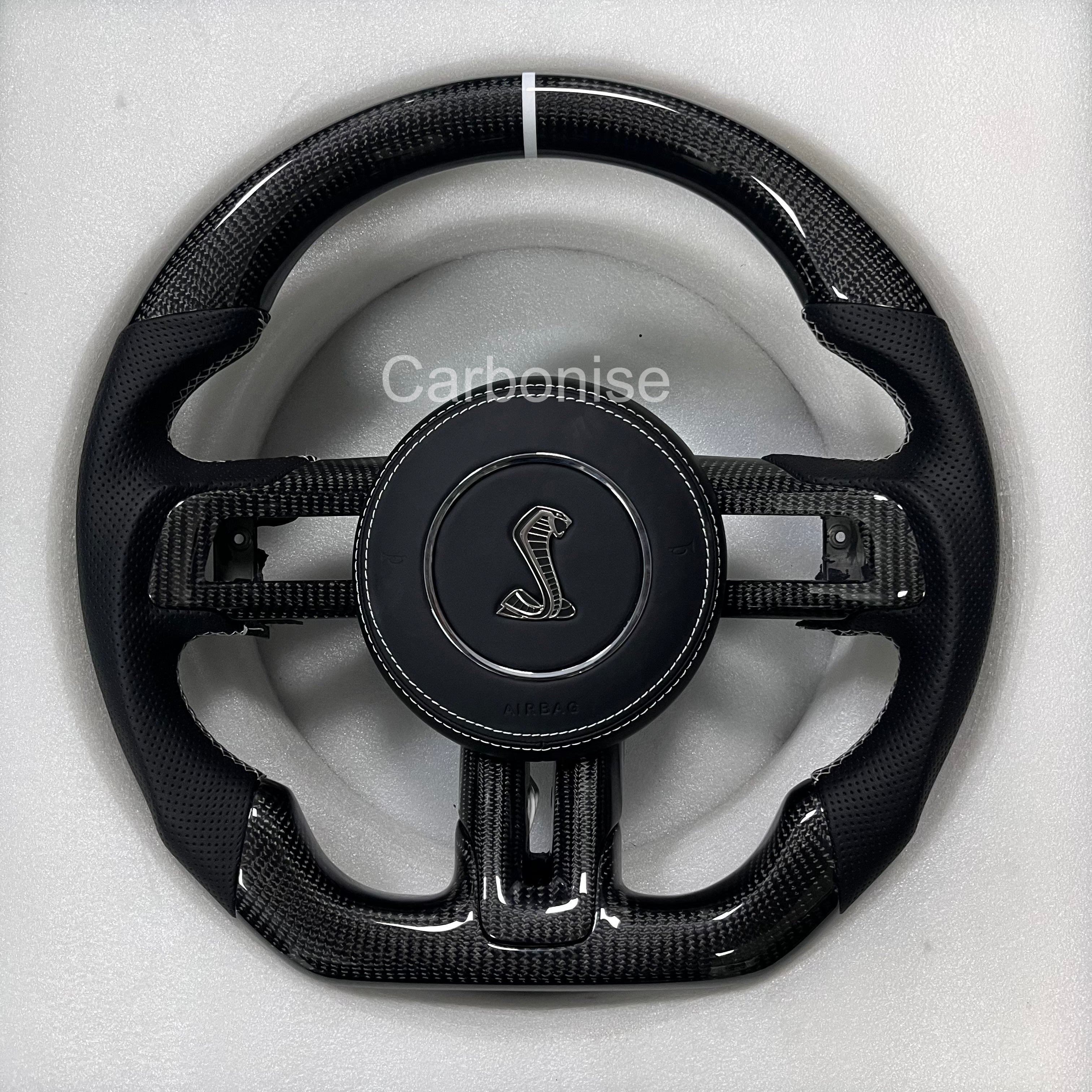 Ford Mustang  carbon fibre steering wheel with perforated leather grips, white center stripe, flat bottom, and Shelby emblem.