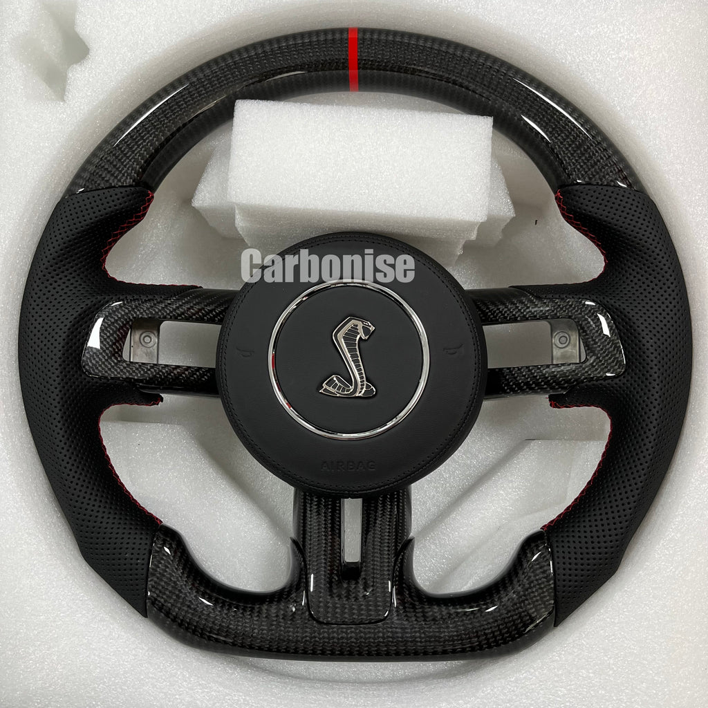 Ford Mustang carbon fibre steering wheel with perforated leather grips, red stitching, flat bottom, and Shelby emblem.