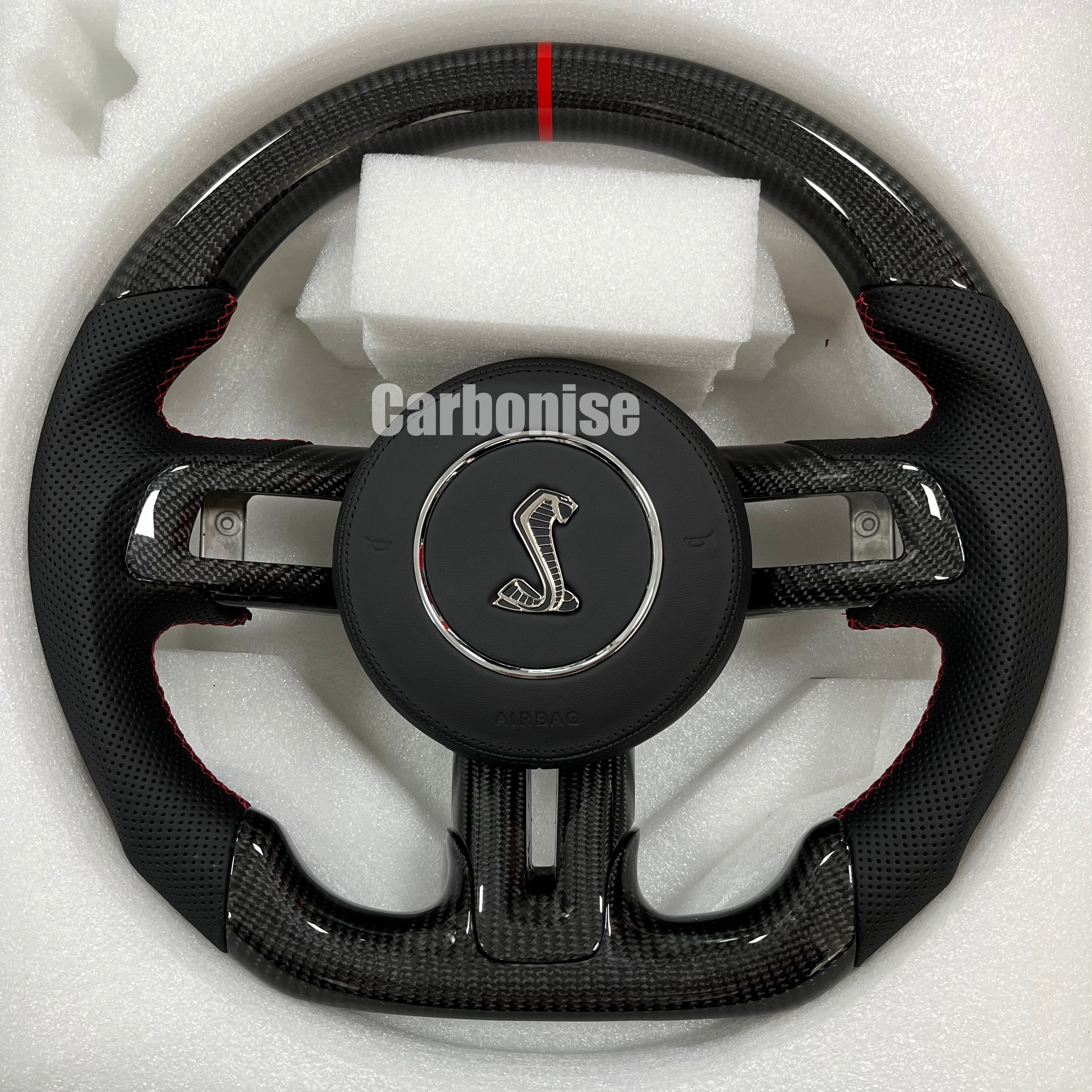 Ford Mustang carbon fibre steering wheel with perforated leather grips, red stitching, flat bottom, and Shelby emblem.