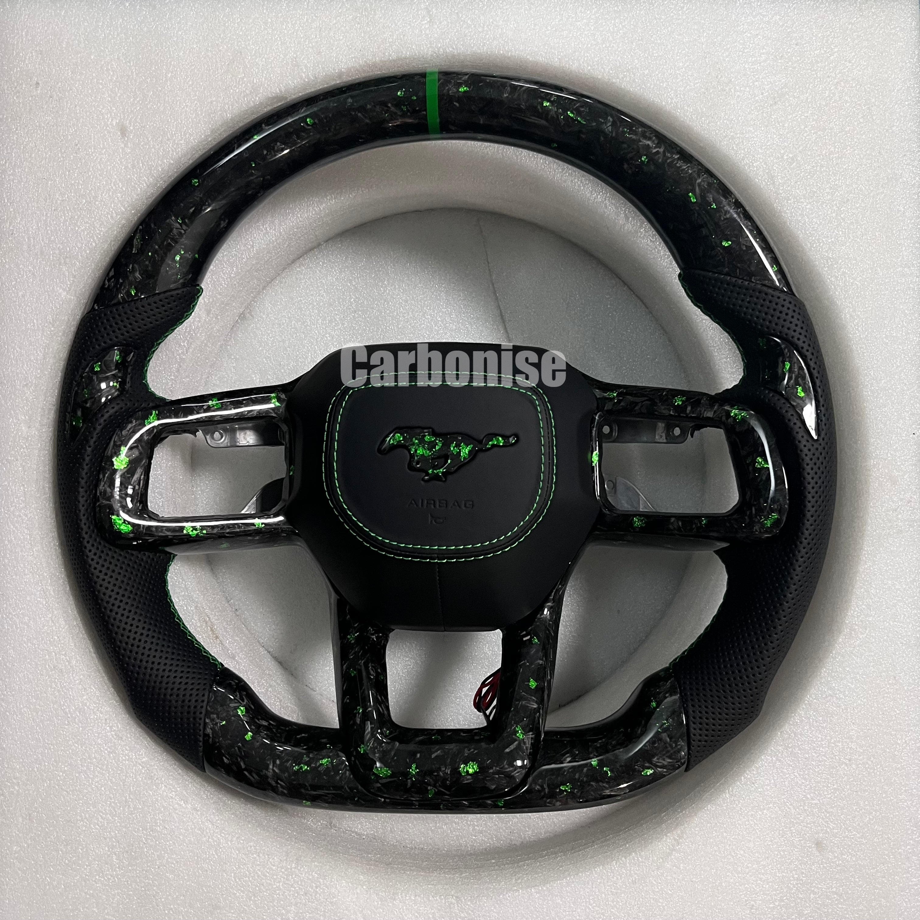 Ford Mustang forged carbon fibre steering wheel with green metallic flakes, perforated black leather grips, green centre stripe, green stitching, matching forged carbon spokes, and OEM Mustang pony airbag.