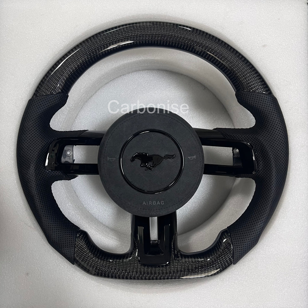 ord Mustang carbon fibre steering wheel with gloss carbon top and bottom, perforated black leather grips, round design, and OEM Mustang pony airbag.