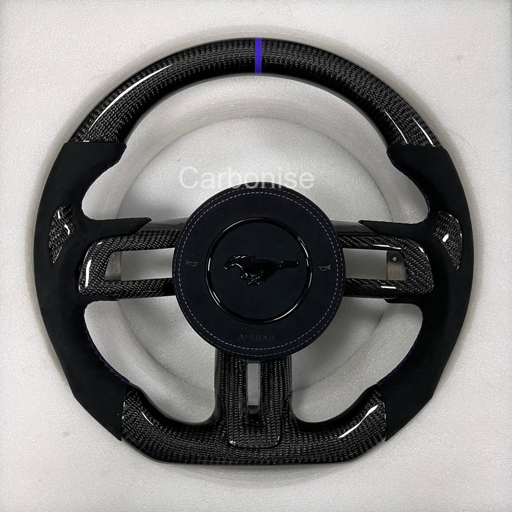 Ford Mustang carbon fibre steering wheel with blue centre stripe, perforated black leather grips, blue stitching, round design, and OEM Mustang pony airbag.