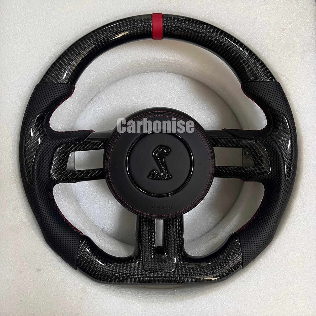 Ford Mustang carbon fibre steering wheel with red centre stripe, perforated black leather grips, red stitching, round design, and Shelby Cobra airbag.