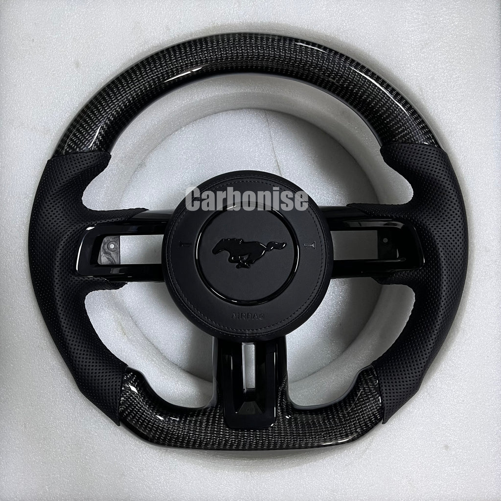 Ford Mustang carbon fibre steering wheel with gloss black carbon top and bottom, perforated black leather grips, matching centre spokes, round design, and OEM Mustang pony airbag.
