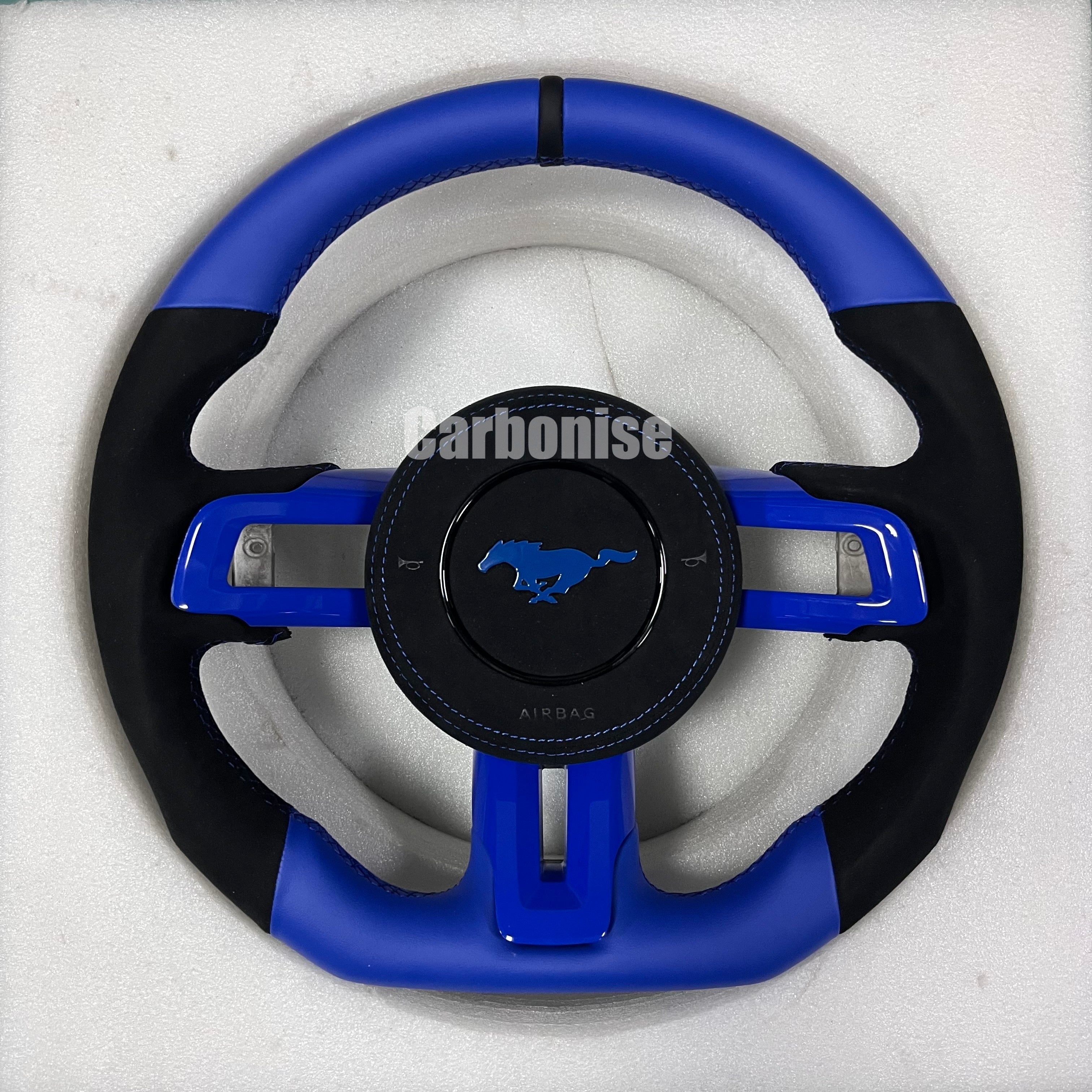 Ford Mustang blue steering wheel with blue leather top and bottom, black Alcantara side grips, blue stitching, blue centre spokes, black centre stripe, and OEM Mustang pony airbag.