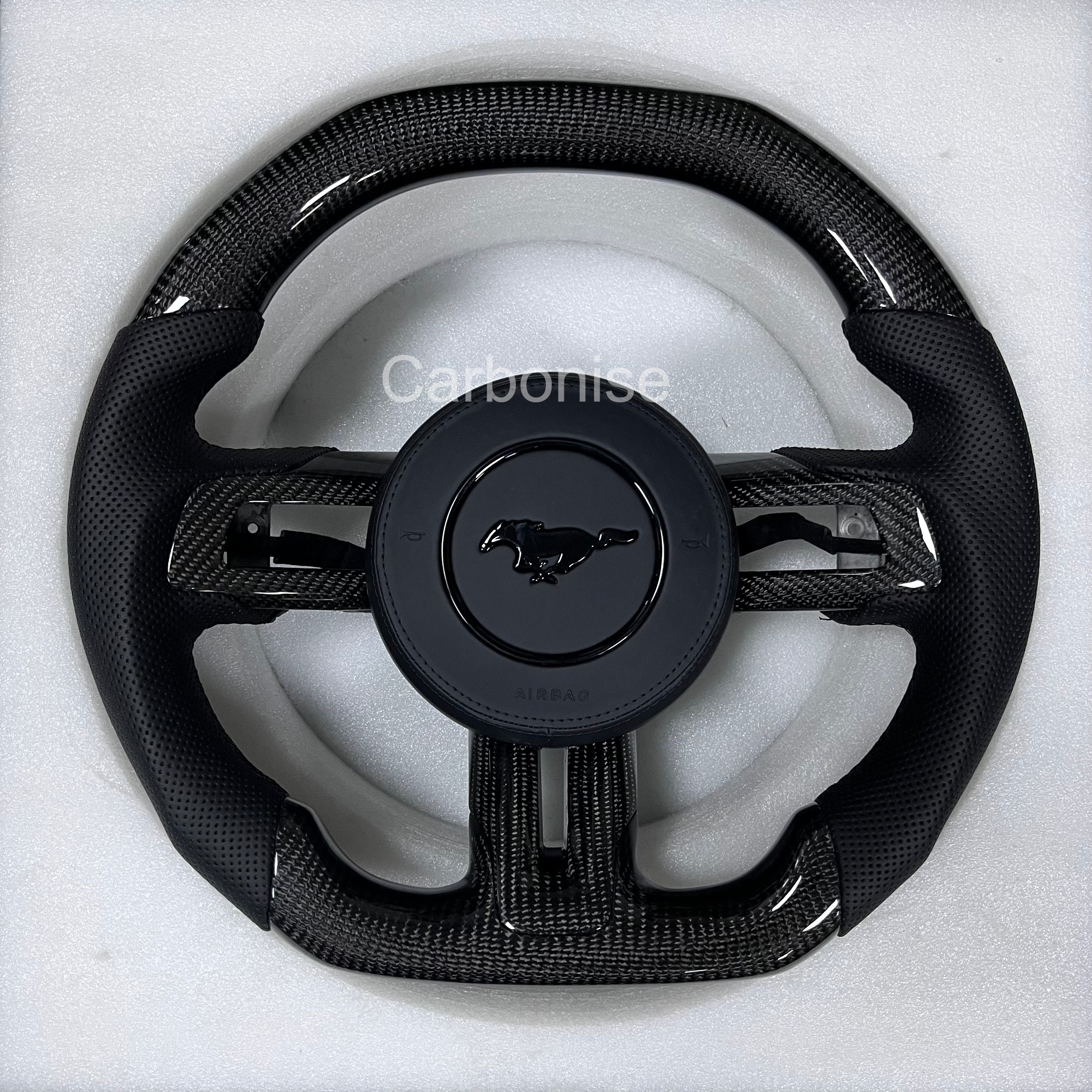 Ford Mustang gloss black carbon fibre steering wheel with perforated black leather grips, round design, and OEM Mustang pony airbag.