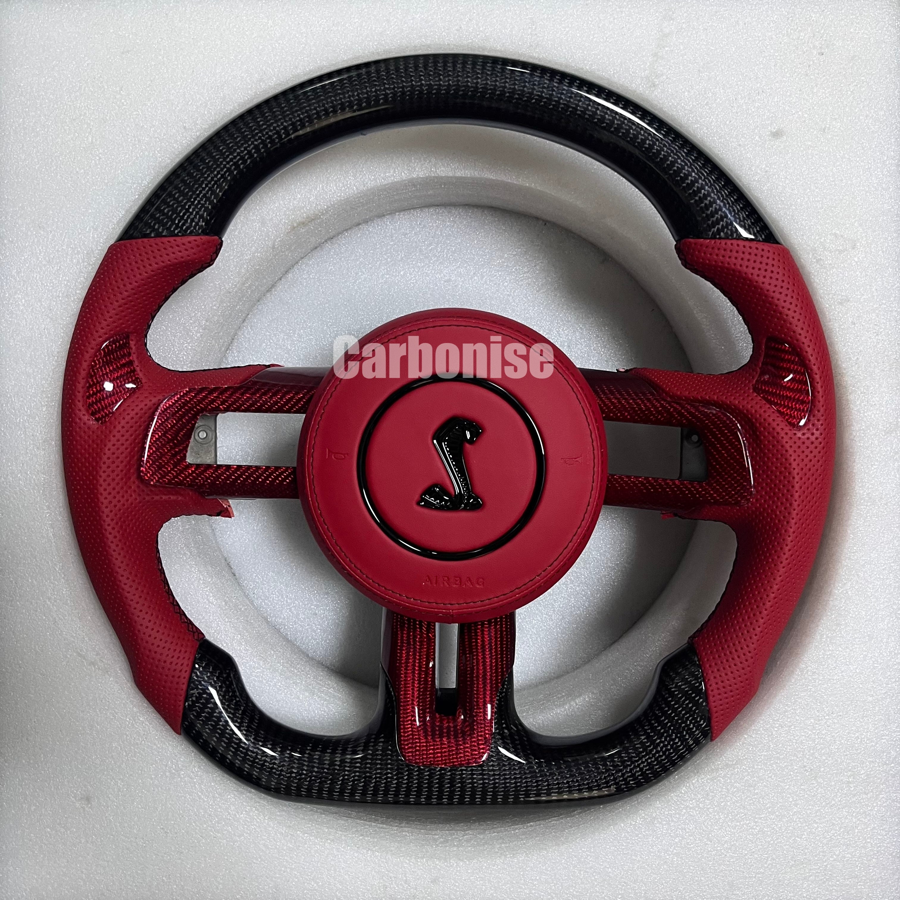 Ford Mustang carbon fibre steering wheel with red perforated leather grips, red carbon centre spokes, gloss black carbon top and bottom