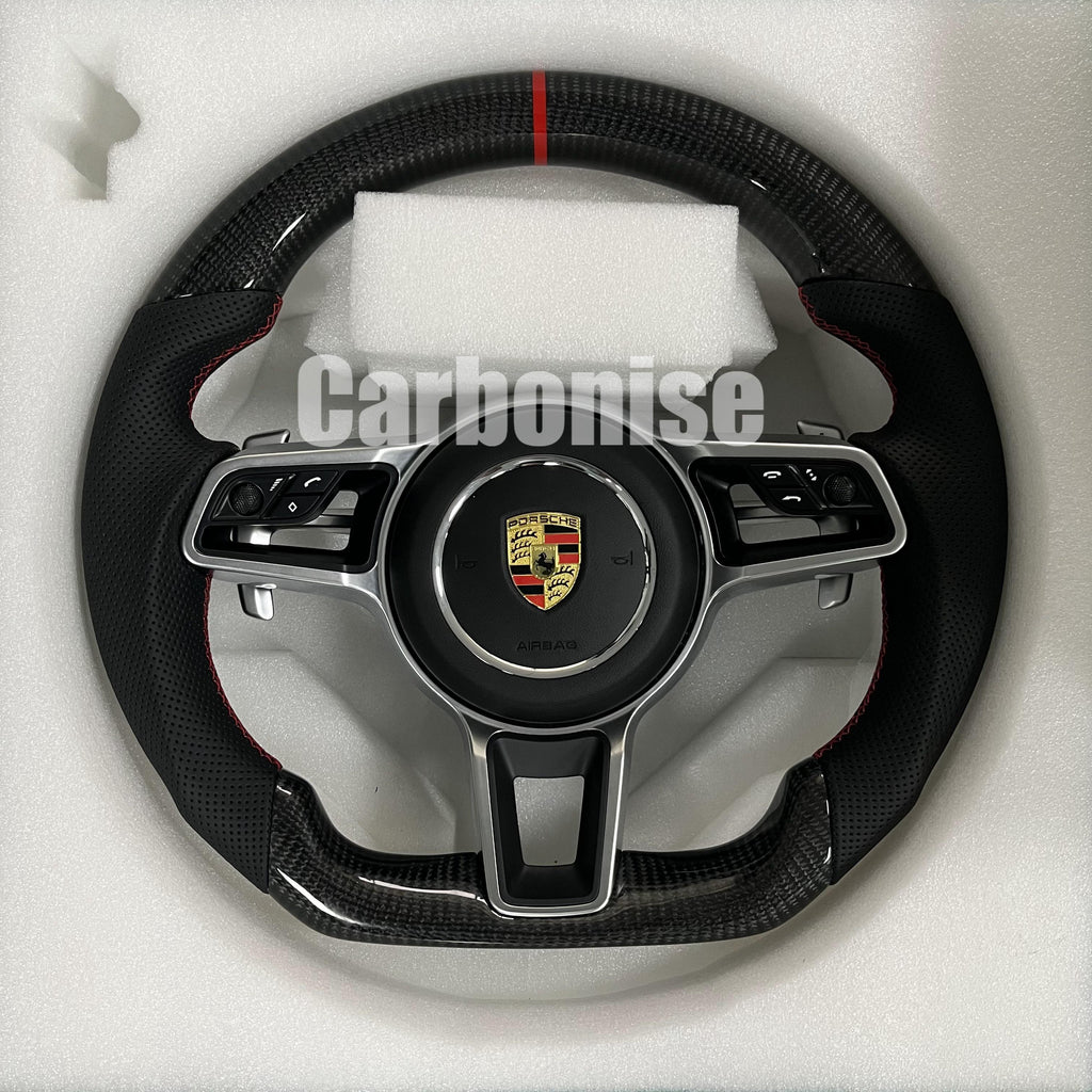 Custom Porsche performance steering wheel featuring high-gloss carbon fiber, a red top racing stripe, and integrated silver multi-function control hardware.
