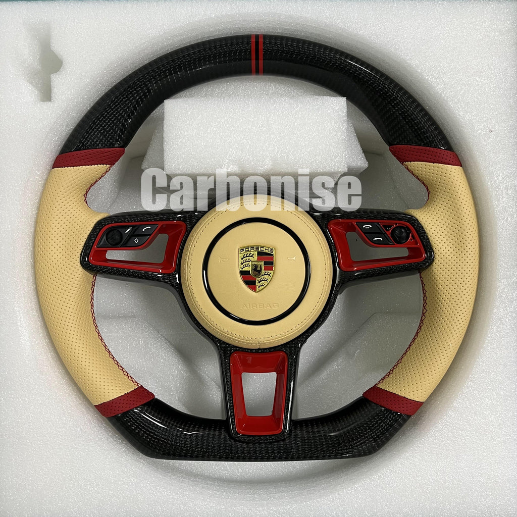 Custom Porsche performance steering wheel featuring high-gloss carbon fiber, a double red racing stripe, and cream perforated leather side grips with red stitching.
