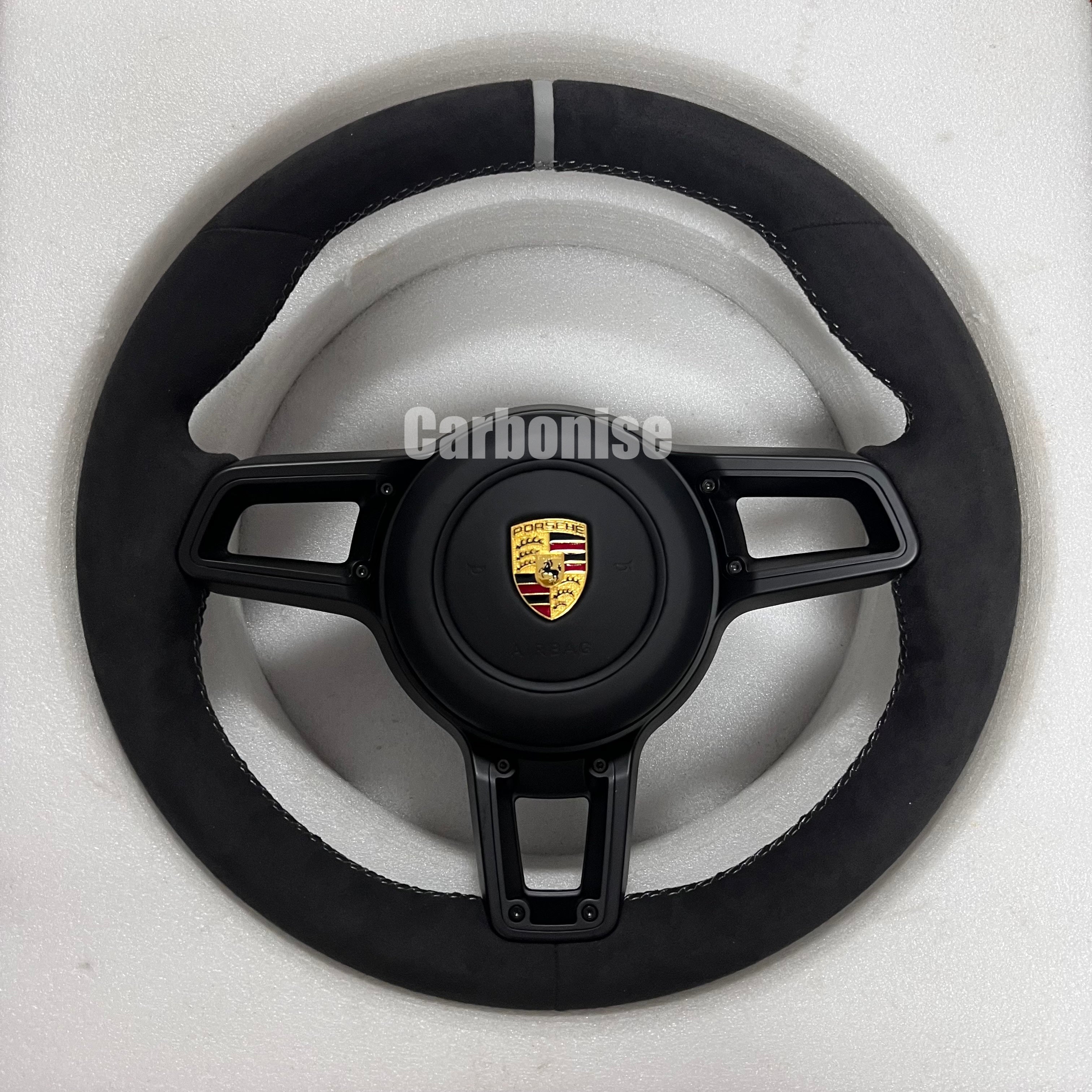 Custom Porsche performance steering wheel featuring a full black Alcantara wrap, a silver top racing stripe, and black multi-function control hardware.